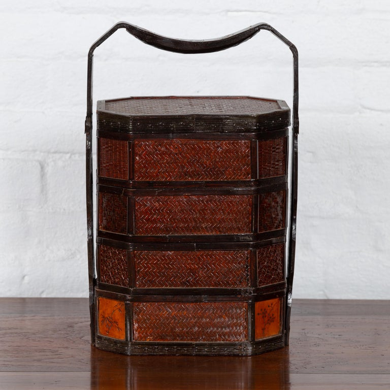 A small Burmese vintage stacking picnic basket from the mid-20th century with lacquered floral motifs and large handle. Born in Burma during the midcentury period, this charming vintage stacking picnic basket features a rattan over wood structure.