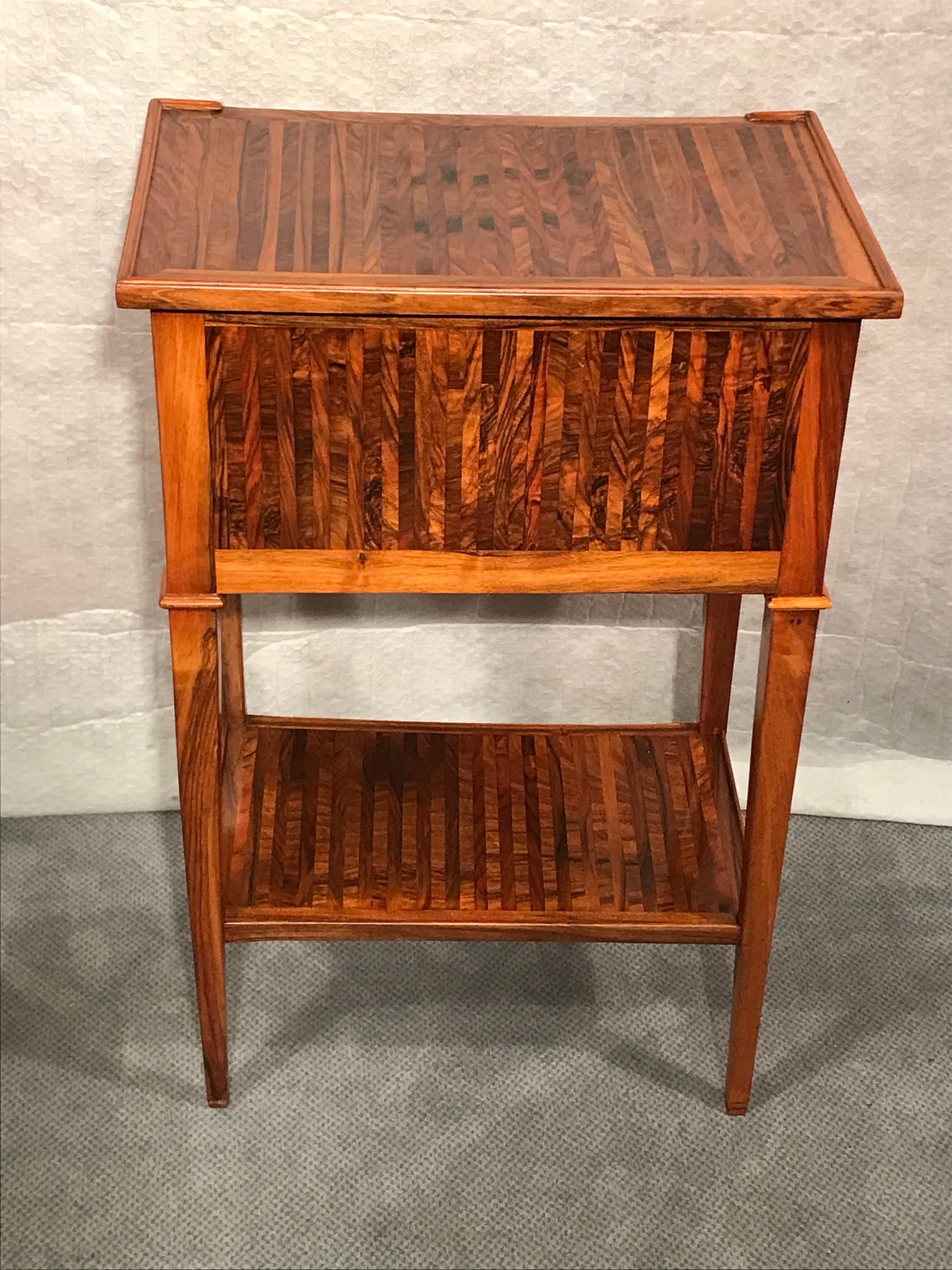 This small chest of drawers or nightstand dates back to around 1790-1800. It comes from Germany. The small chest of drawers stands on four slender pointed legs. It has two drawers and a shelf in the lower part. The special feature of this unique