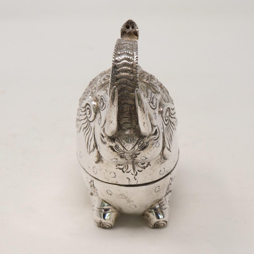 Small Cambodian Silver Elephant Box. A traditional sturdy crouching elephant form with front legs tucked beneath him and the hind kneeling underneath. The hammered silver  with caparisoned saddle blanket on the spotted body with tusks and trunk