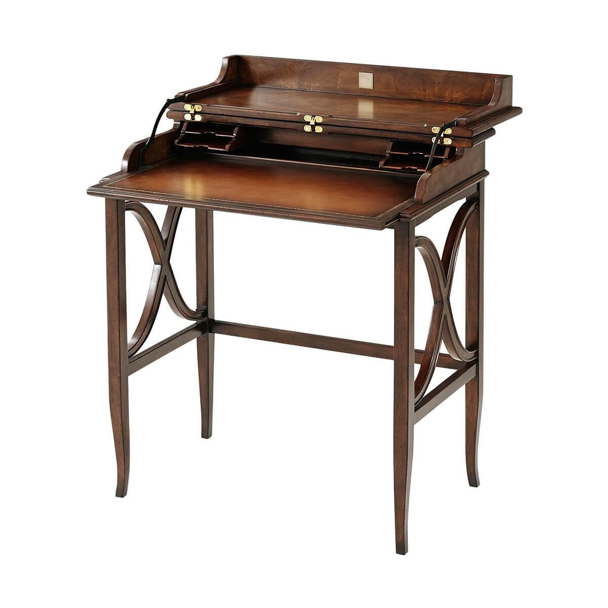 A Campaign style mahogany campaign desk, the circular crossbanded molded edge top hinged and folding open to reveal an interior with pigeon holes and a leather writing surface above square tapering and splayed legs joined by wavy 'X' stretcher to