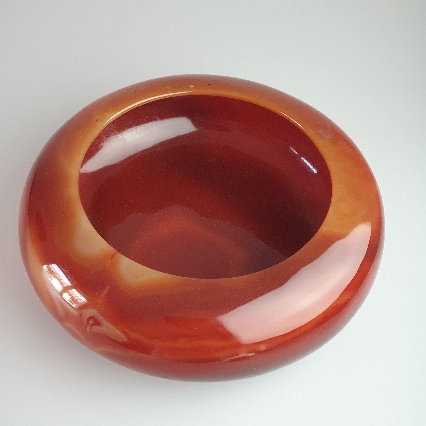 Enriched with delicately rounded edges, this empty-pocket bowl boasts a sophisticated range of colors that goes from a dark red to a pale-pink. Manufactured from a single piece of clear carnelian agate and adorned with a polished finish for a