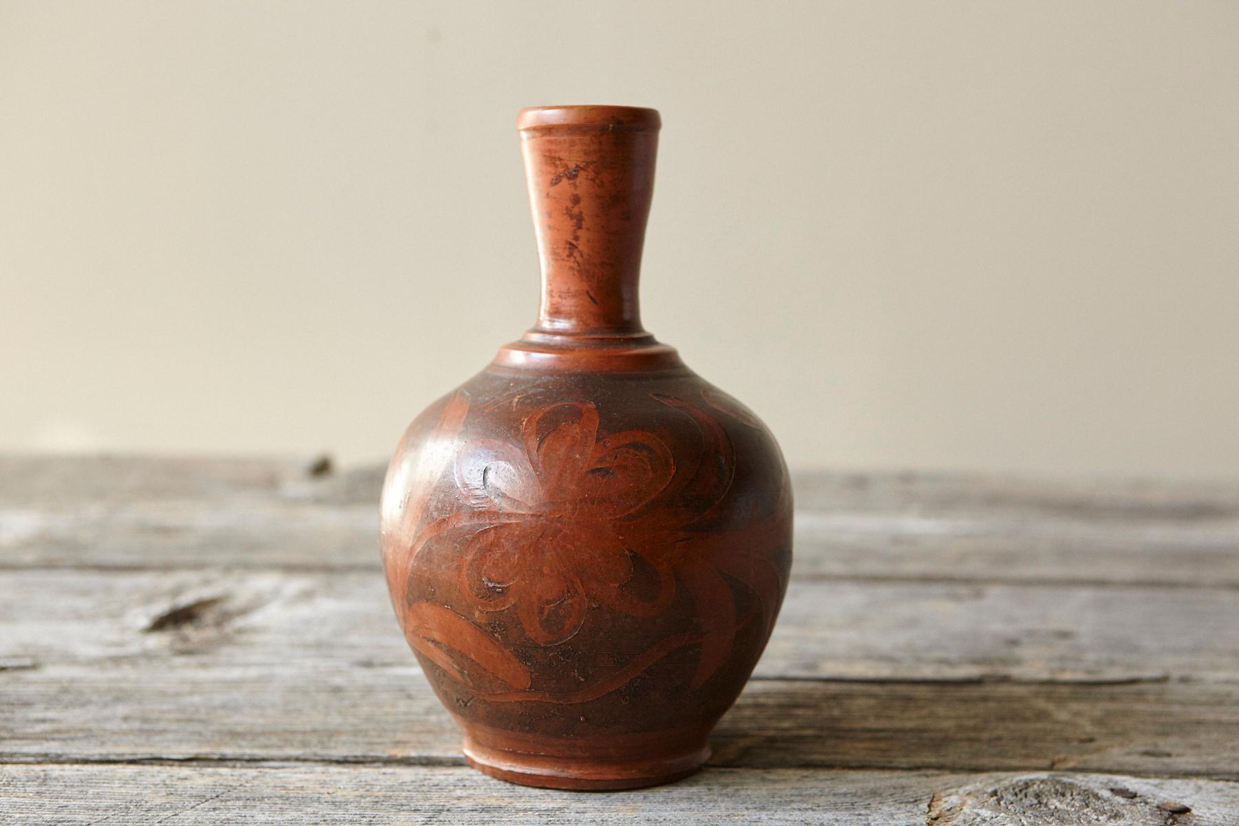 Vaso compatto in terracotta lavorata a ruota, metà del XX secolo, circa 1940-1960. La forma ha un corpo arrotondato che sale fino a un collo cilindrico stretto con un bordo leggermente ispessito. La superficie è rifinita in una calda barbottina