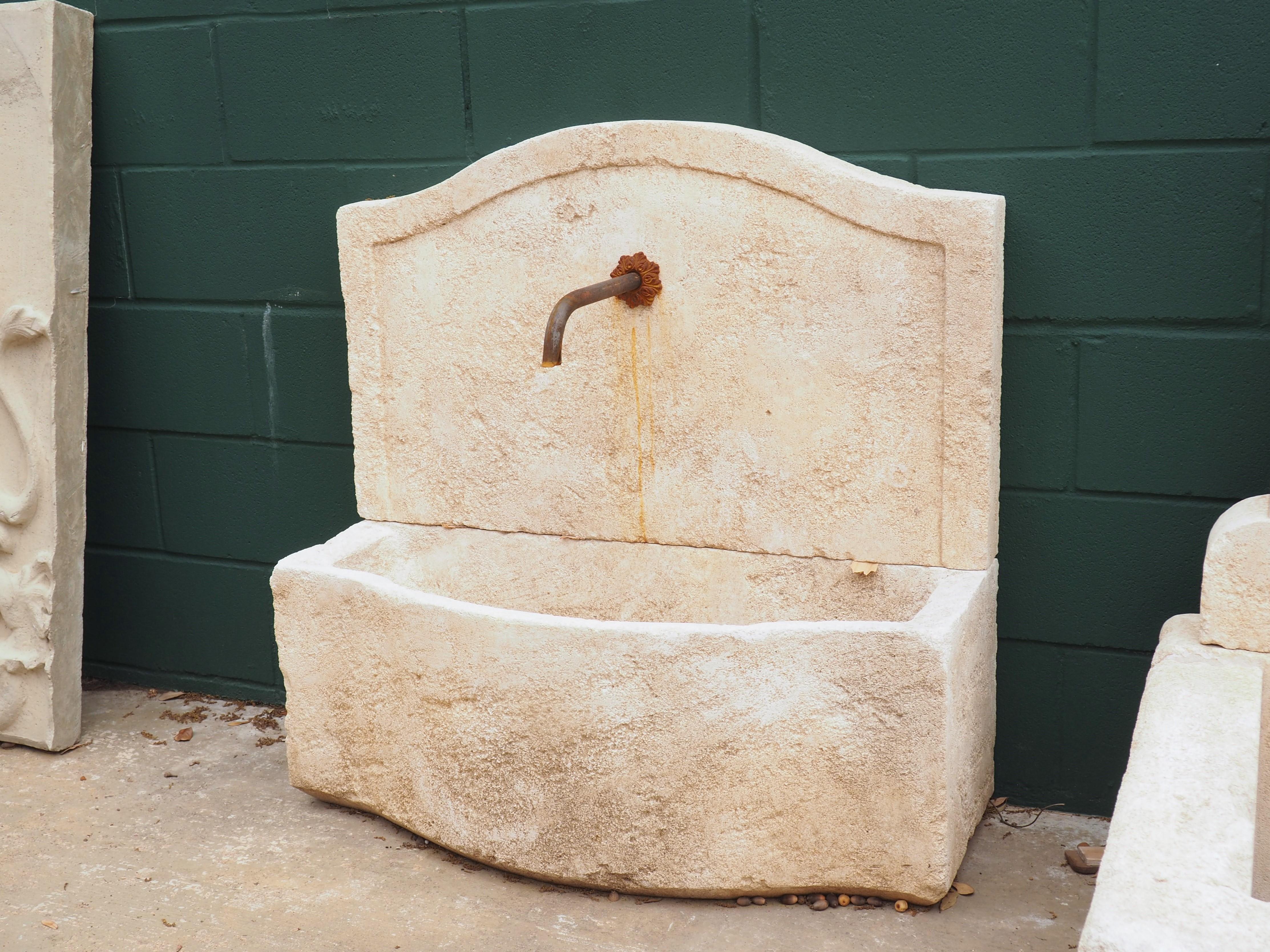 This small, rustic wall fountain was hand carved in the South of France with local limestone. An artistic French finishing technique has been used to give the appearance of age, while exposure to the elements has provided a nice cream and white