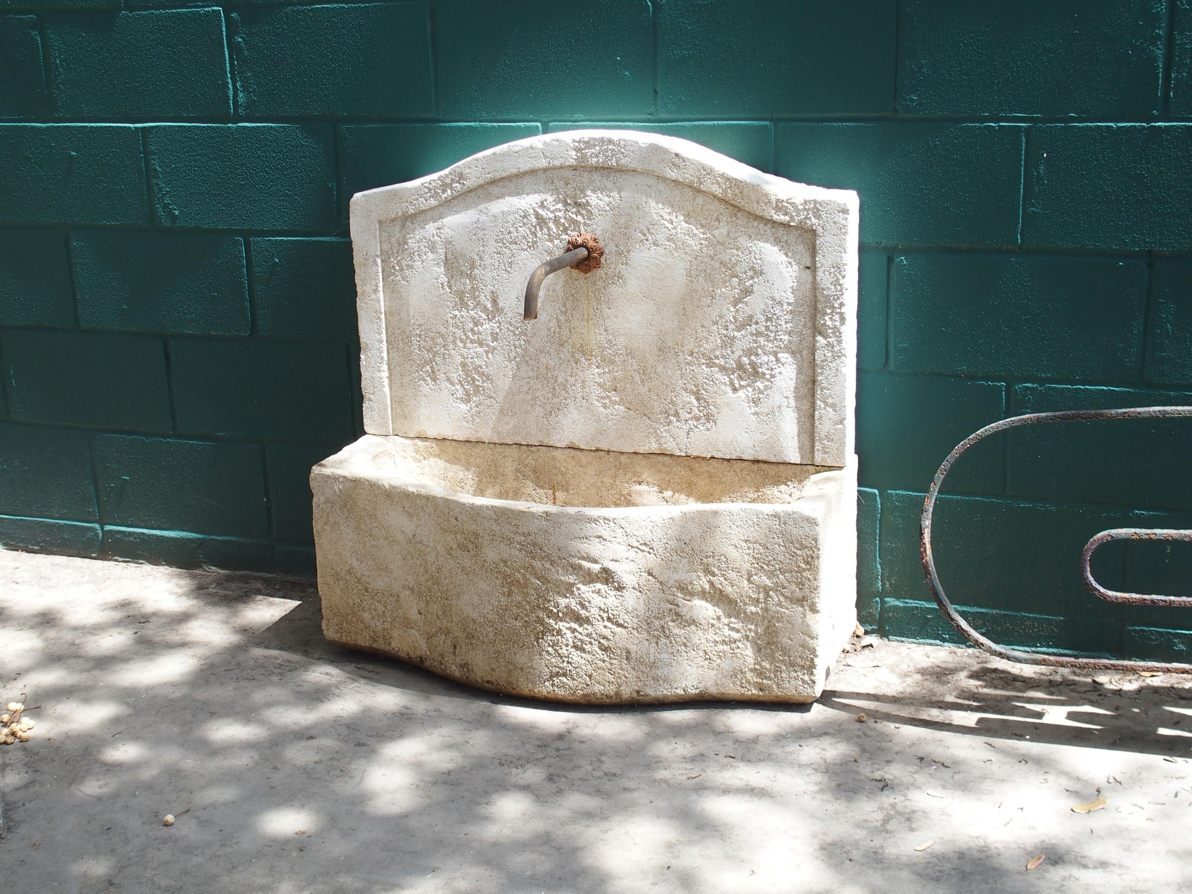 This small, rustic wall fountain was hand-carved in the South of France with local limestone. An artistic French finishing technique has been used to give the appearance of age, while exposure to the elements has provided a nice cream and white