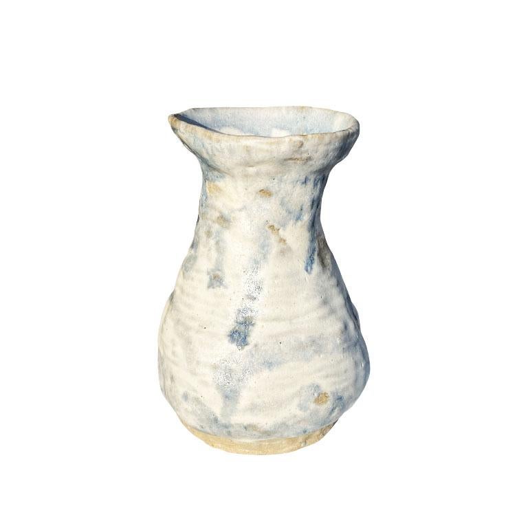 A beautiful small ceramic pinch pot vase. Created from clay, this fun piece will be fantastic used in a grouping of other vases and filled with your favorite blooms. Glazed in a soft pale blue and white, it will complement any room.
