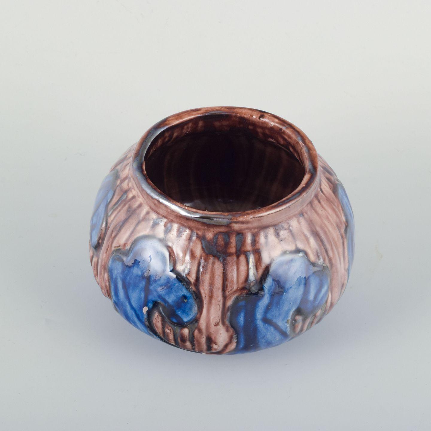 Attributed to Møller & Bøgely, small stoneware vase. 
Made around 1918–1922. 
The vase is decorated with a relief pattern and glaze in shades of brown and deep blue with lively surface effects. 
Classic rounded form with distinct relief