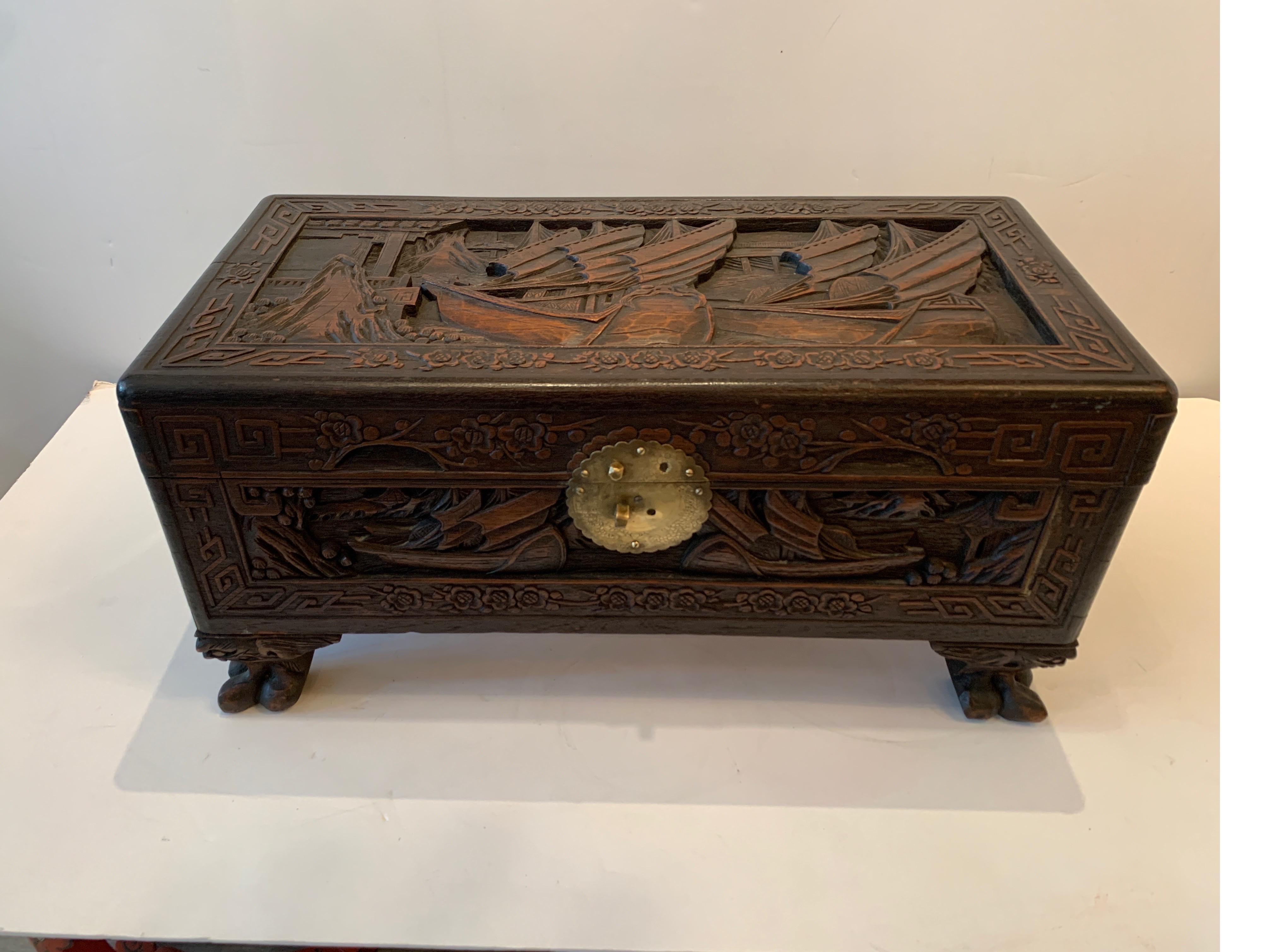 A hand carved Chinese large table box with hinged lid. Intricately carved all-over with Asian carvings resting of four paw feet. Bronze lock plate on front.