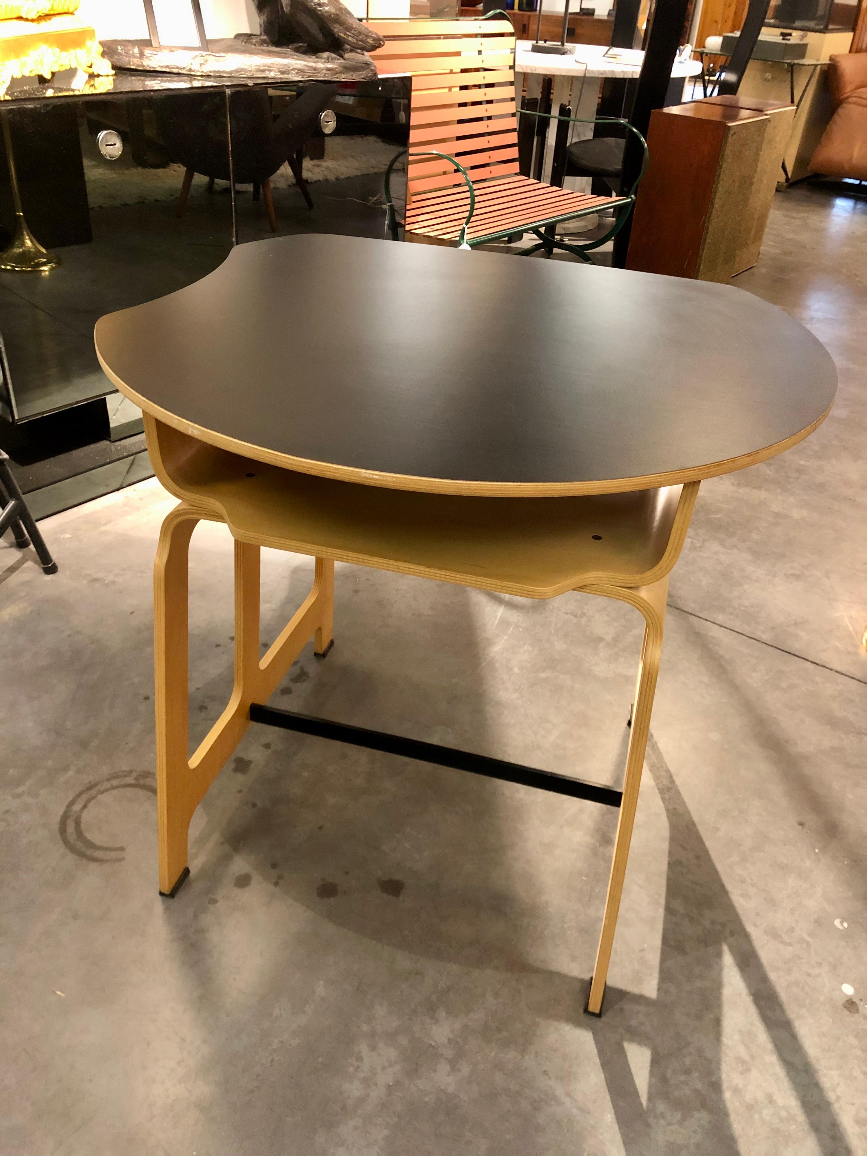 Petit bureau pour une salle de classe présenté à la 12e Triennale de Milan en 1960 par Jules Wabbes pour la Belgique.
Noyer noir africain (mansonia) stratifié et moulé, dessus en vinyle, repose-pieds en aluminium noir.
Il s'agit d'une édition