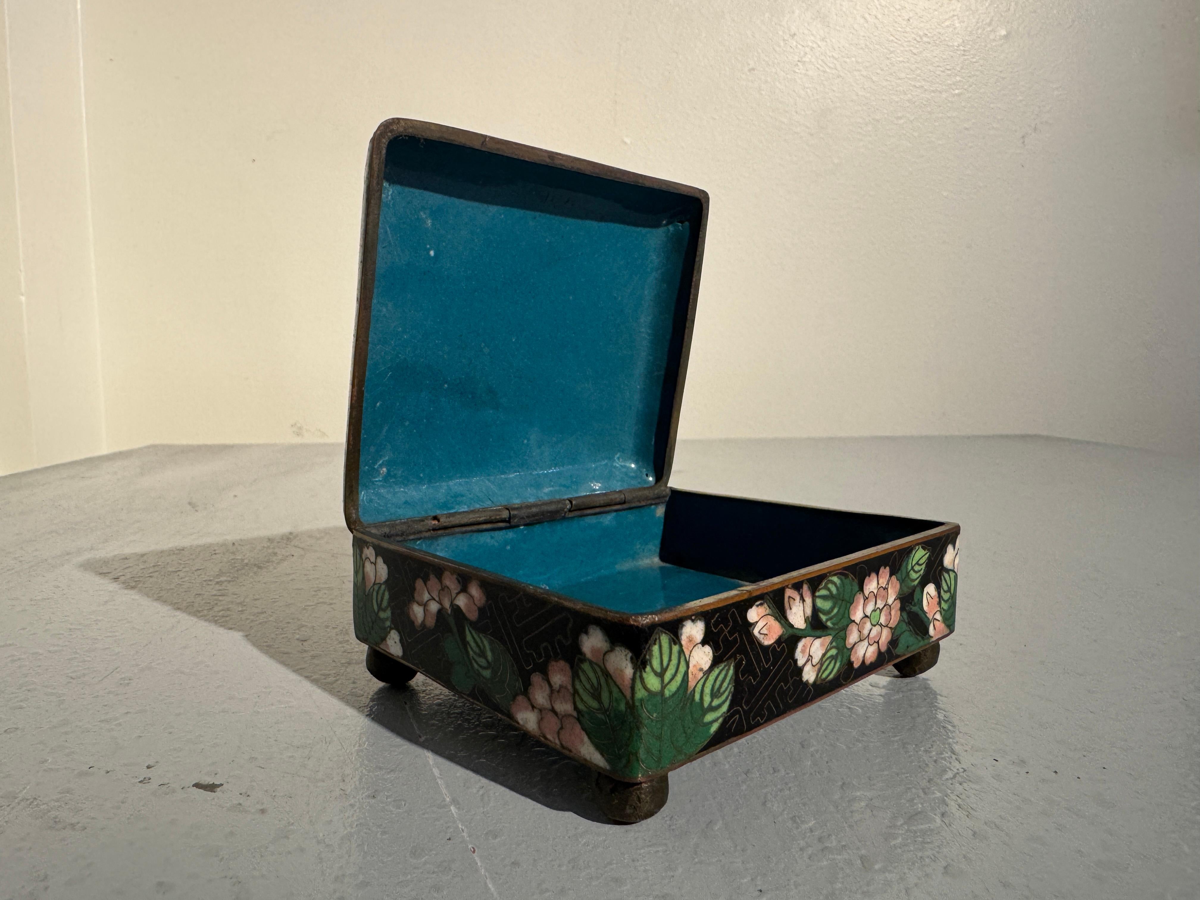 Pequeña y preciosa caja china de cloisonné negro con diseño de peonías, finales de la dinastía Qing, hacia 1900, China.

La cajita de cloisonné se eleva sobre cuatro patas en forma de bollo y está decorada con un diseño de peonías en flor sobre un