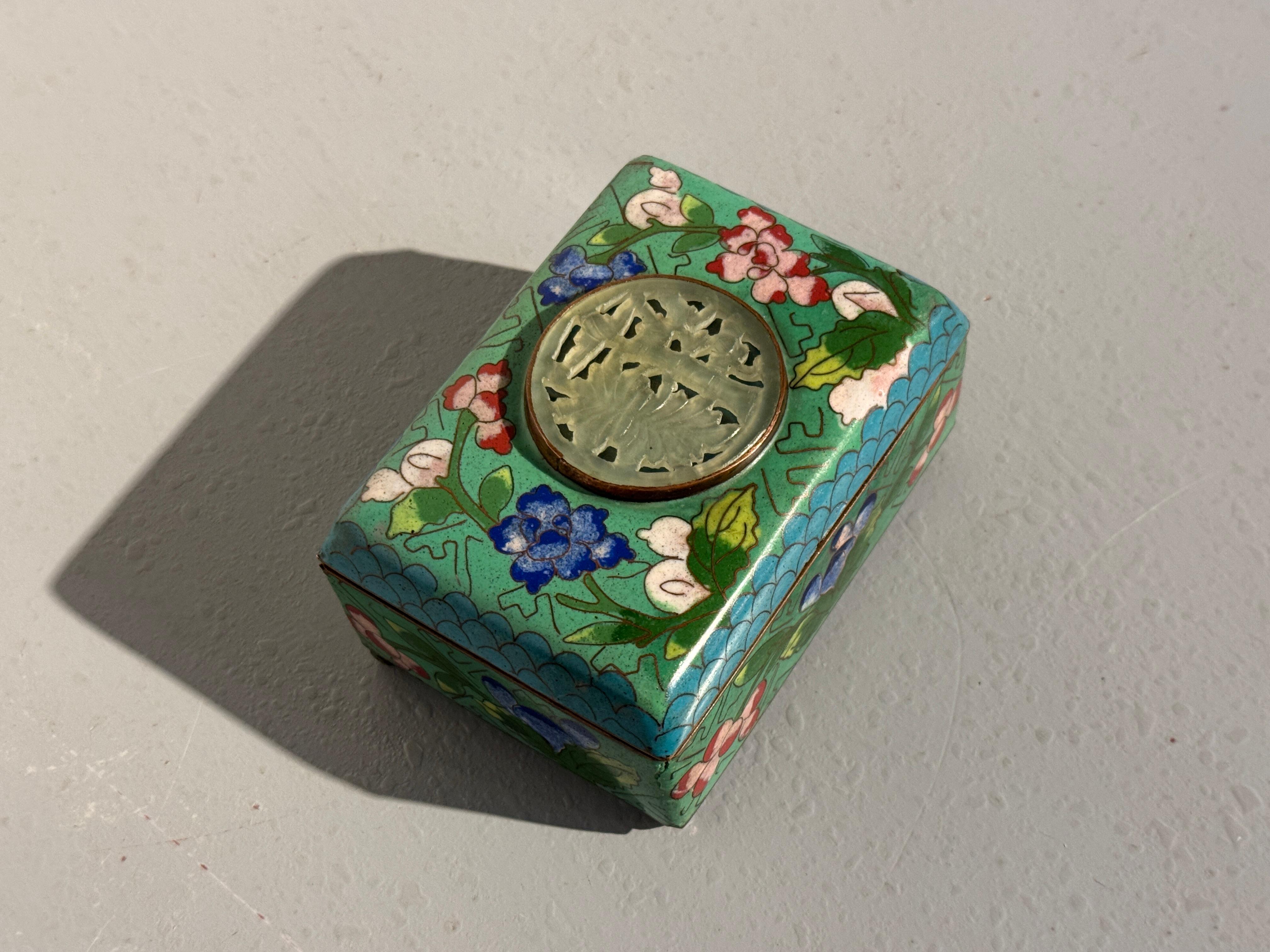 Preciosa caja de baratijas pequeña de cloisonné de exportación china con un redondel de piedra dura tallada, Periodo de la Primera República, hacia 1915, China.

La cajita de cloisonné está colocada sobre cuatro patas cortas, y presenta un diseño de
