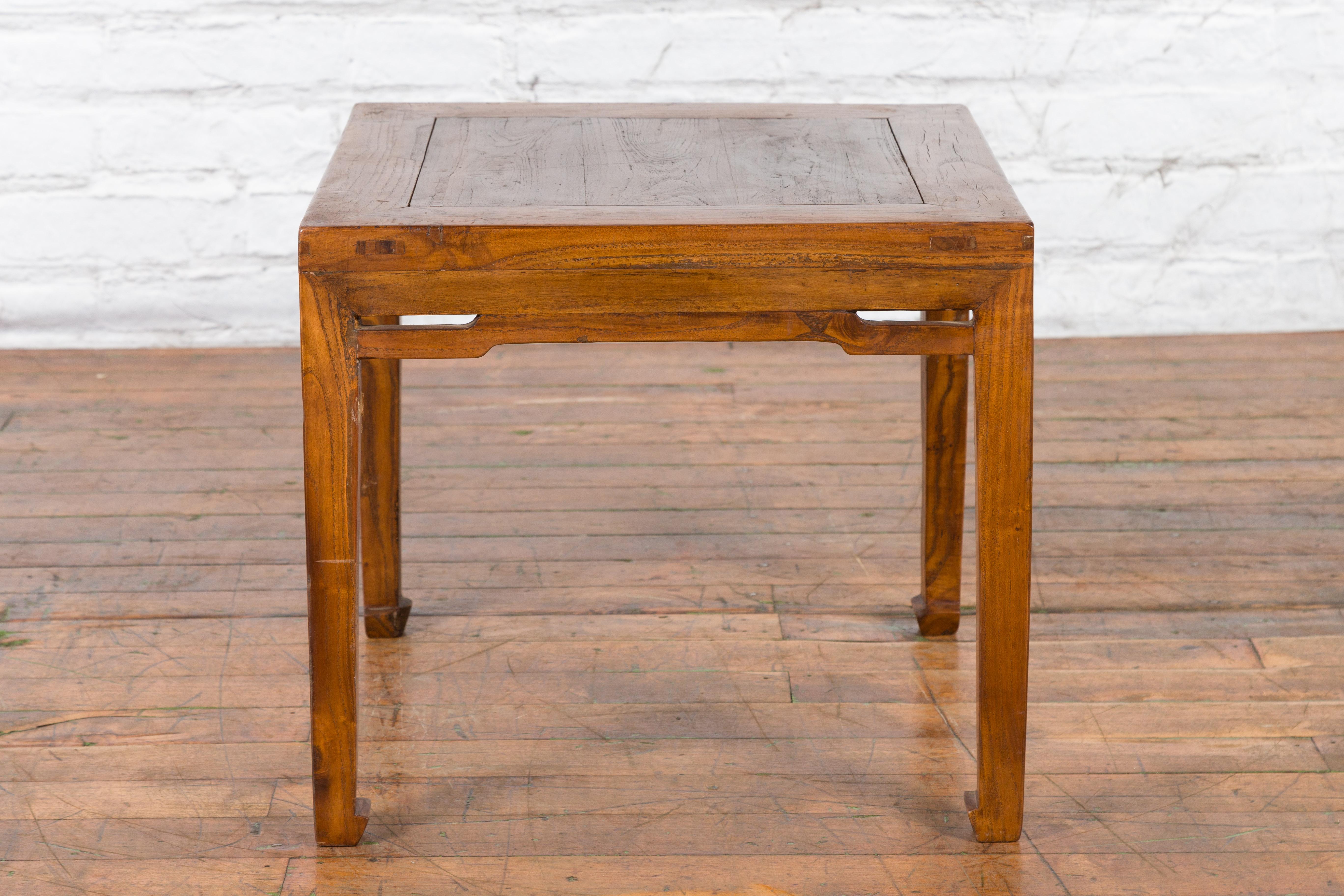 An antique Chinese coffee table from the early 20th century with humpback stretchers and horse hoof extremities. Created in China during the early years of the 20th century, this small coffee table features a square top with central board, sitting