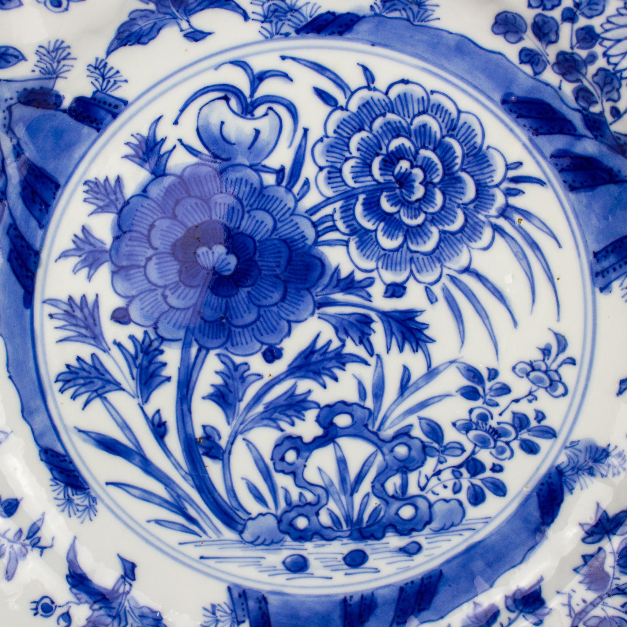 A small Chinese porcelain dish, East India Company, Qing Dynasty (1644-1912), Kangxi Period (1662-1722). Decorated with underglaze blue depicting floral and vegetal motifs in the center and rim. In the back we can see some vegetal decoration in the