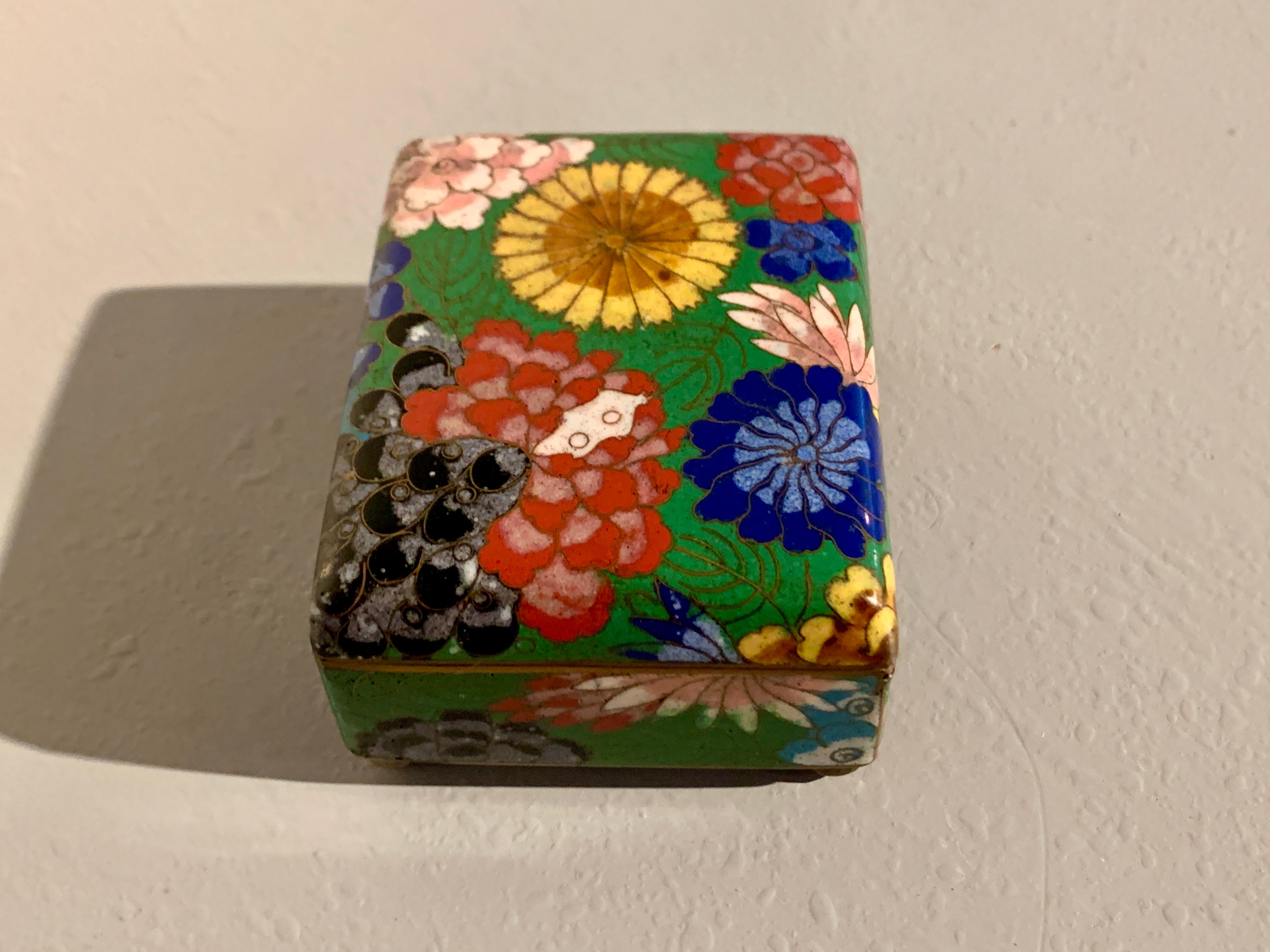 A small a charming Chinese cloisonne trinket box with floral design, Republic Period, circa 1930s, China.

The small copper trinket box decorated in cloisonne enamel technique with bold and bright floral blossoms in shades of yellow, pink, red,