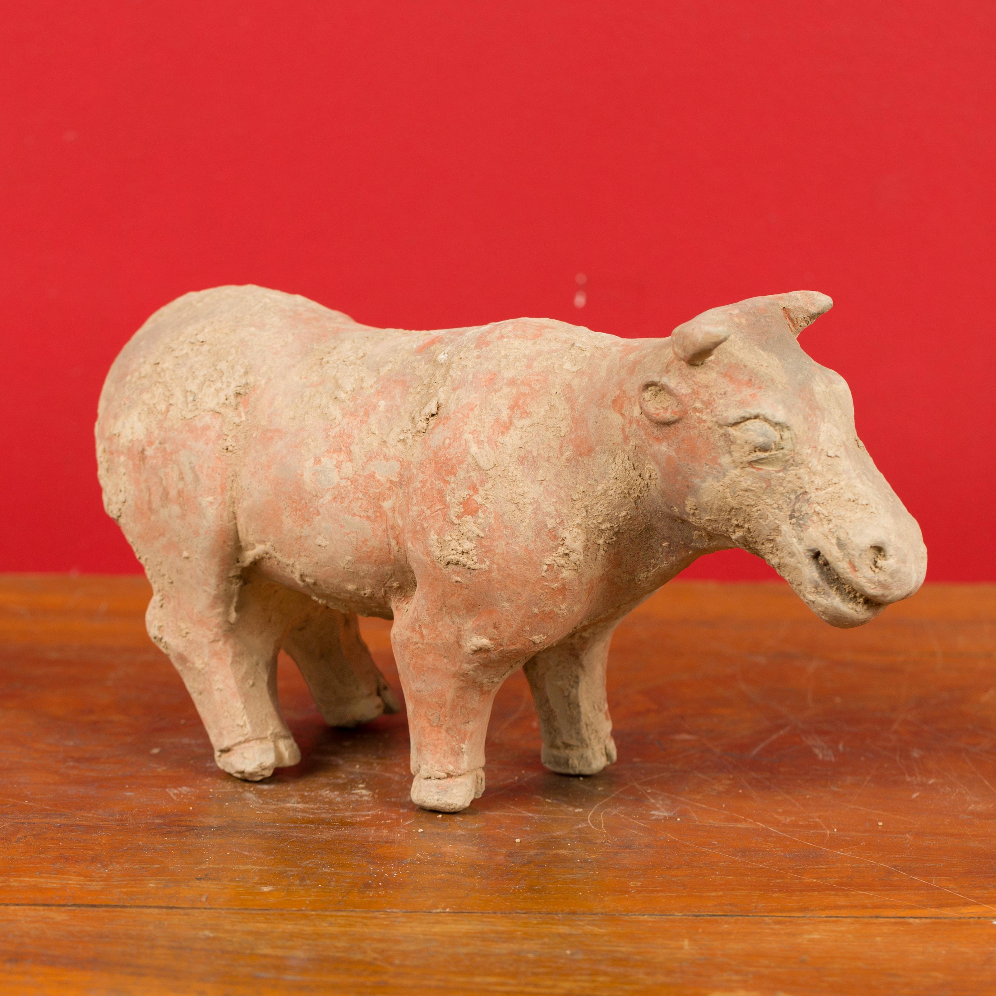 A small Chinese Han Dynasty terracotta bull Mingqi circa 202 BC-200 AD. Born in China during the Han Dynasty, this petite ancient terracotta sculpture presents a bull in standing position. Referred to as a Mingqi, this terracotta bull was likely a