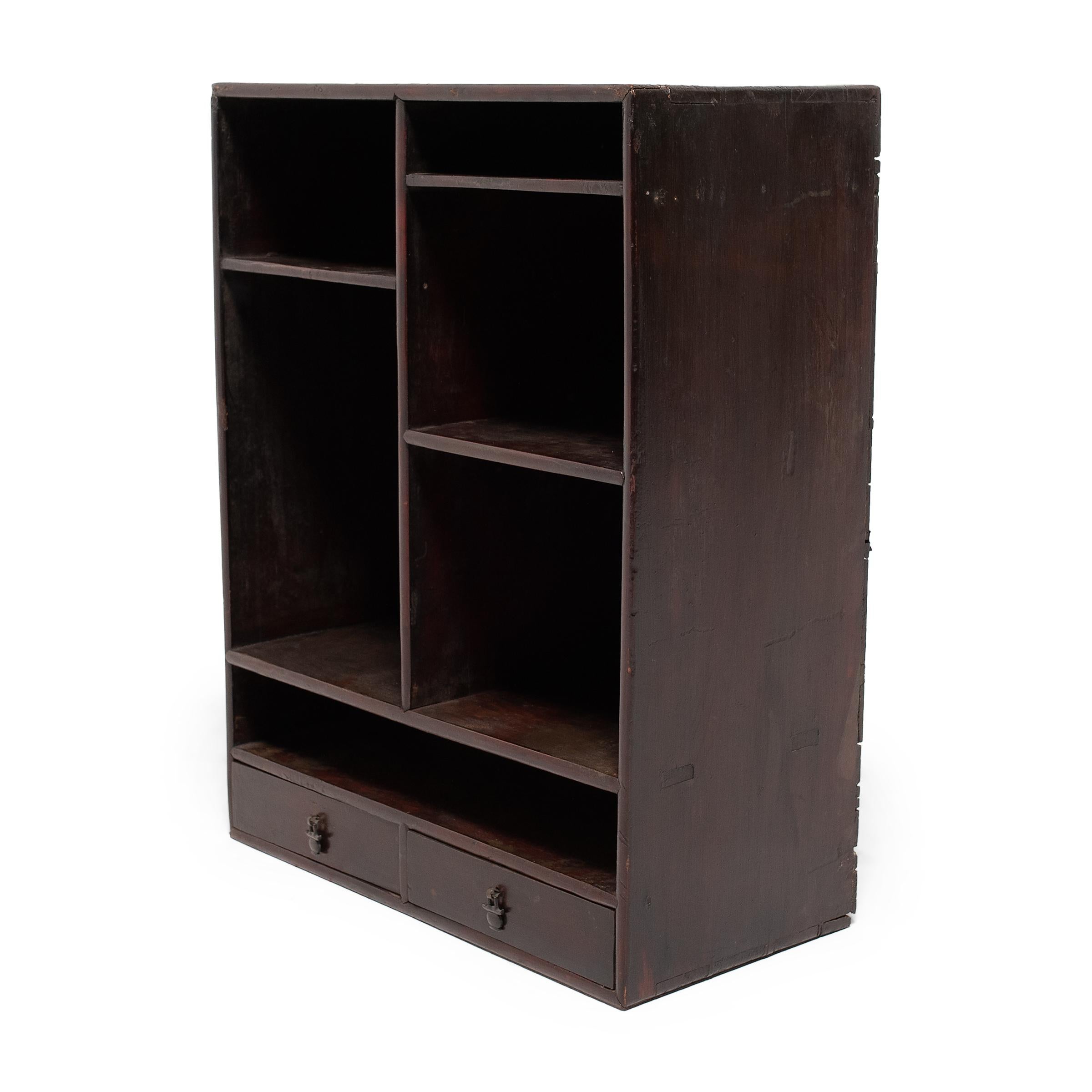 This provincial collector's shelf from the early 20th century once stood in an office or home studio, displaying a curated collection of books, accessories, and precious objects. The low shelf is simply designed with six open compartments of varying