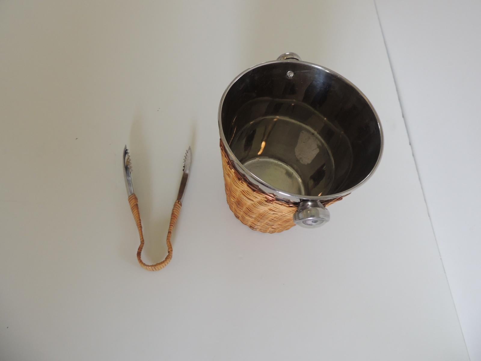 Small chrome and rattan ice bucket with round handles and ice thongs.
Rattan woven with copper wires and the thong is also wrapped in the rattan.
Size: 7
