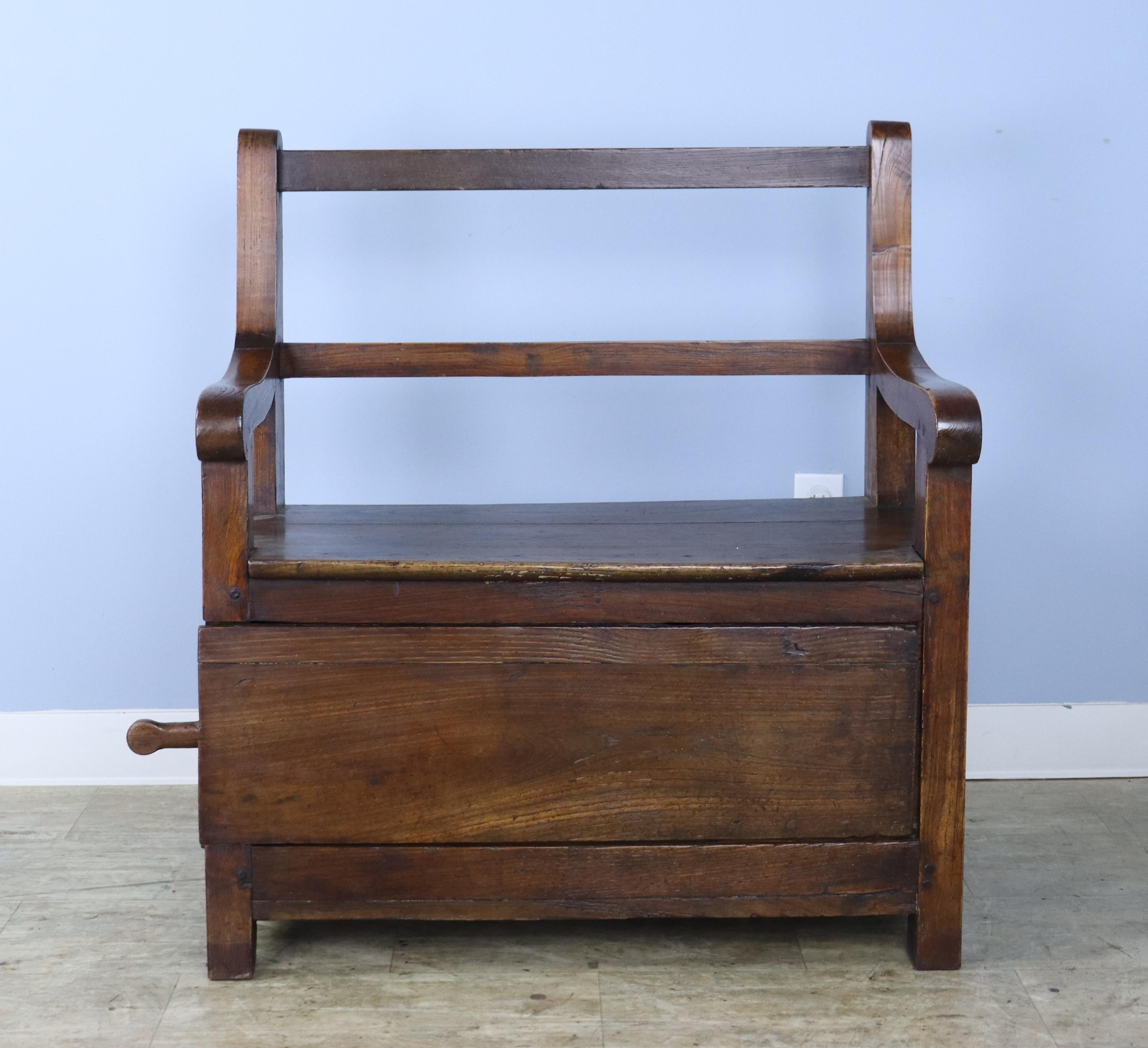 A sweet little bench for the hallway, bedroom or fire side. Mellow chestnut with lovely patina and charming inset panels. The sliding storage door with hand carved handle opens esily to a roomy compartment.