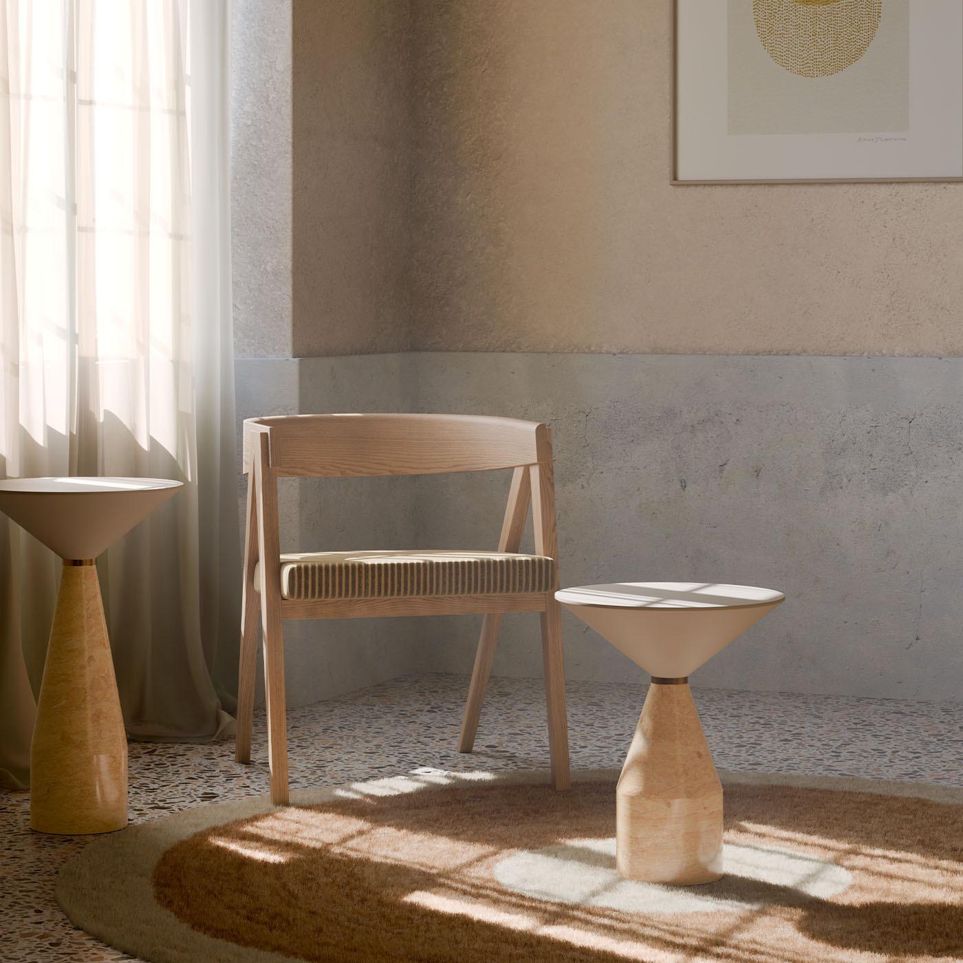 La table d'appoint Cino illustre la fusion sophistiquée de l'art et de la fonctionnalité. Cette pièce unique se caractérise par un remarquable plateau de table fabriqué en frêne massif, élégamment complété par un piètement en luxueux marbre jaune