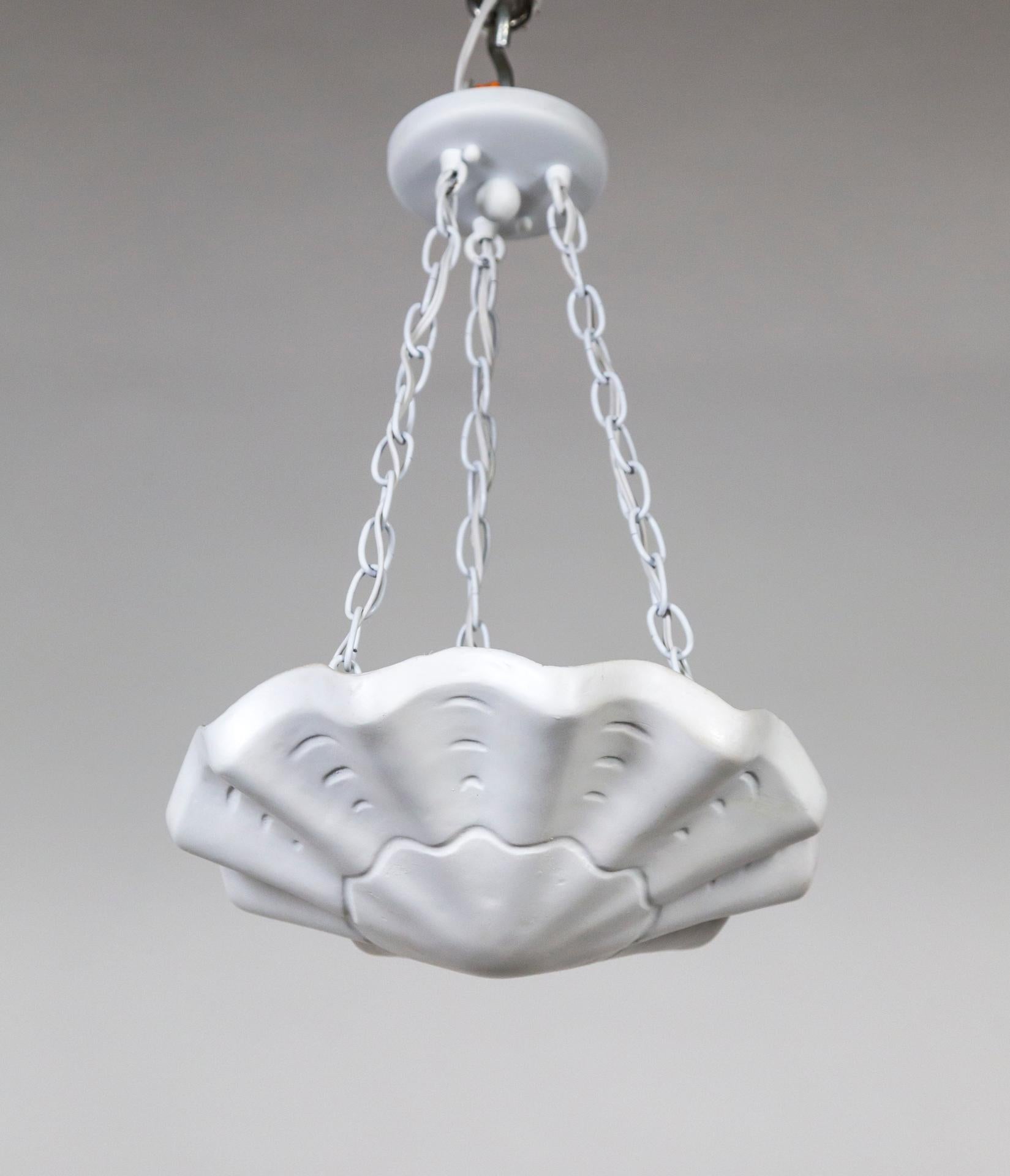 A plaster pendant in an undulating shell shape, with scalloped edges and imprinted lines accentuating the form. A newer take on Francis Elkins's 1940s plaster plafonnier. Hanging by three white chains; with 3 medium base ceramic sockets.