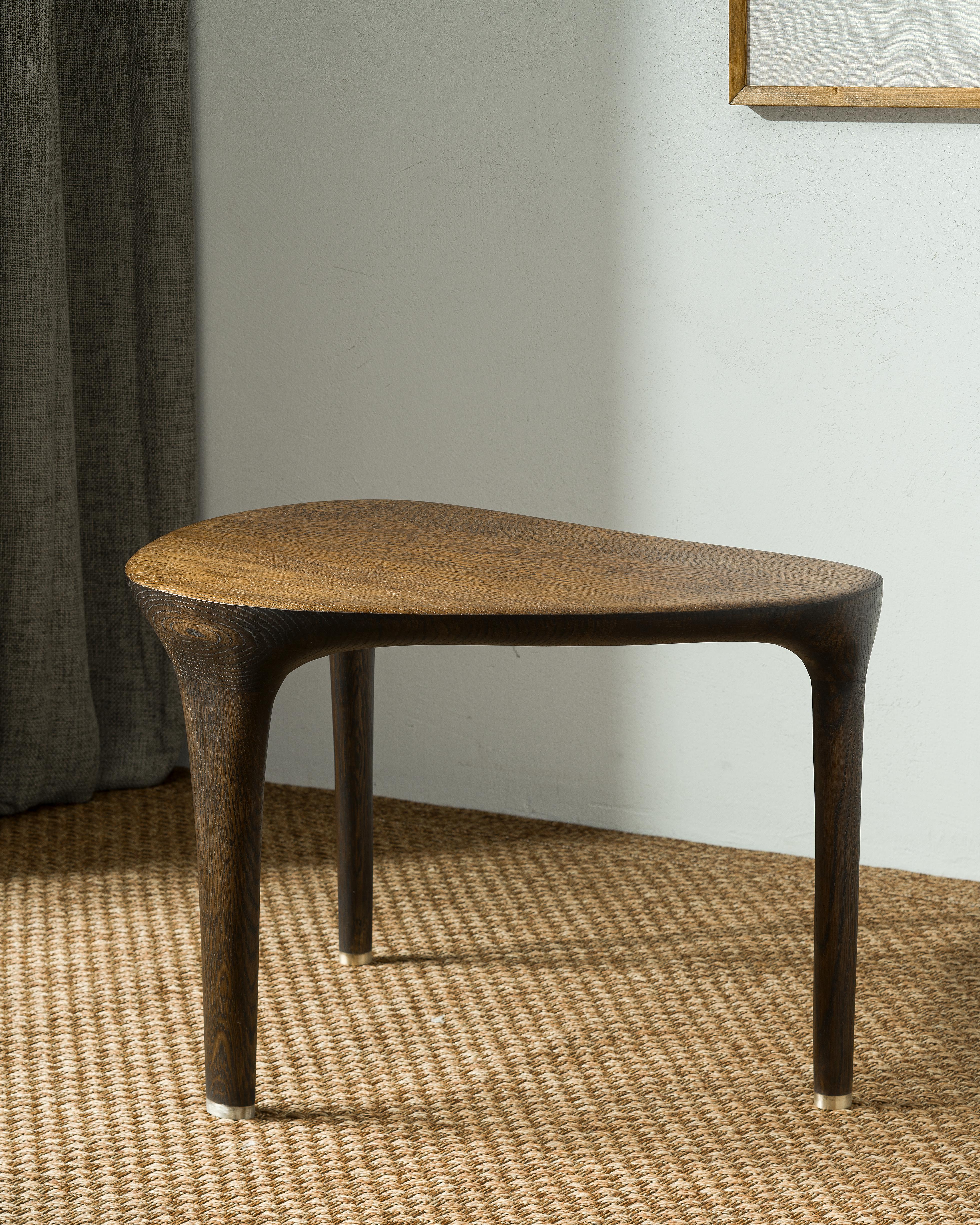 Petite table basse de Tomasz Omachel
Dimensions : D 49 x L 72 x H 45 cm. 
MATERIAL : Chêne, laiton.

Cette table d'appoint finement travaillée allie élégance et simplicité. Cette pièce comporte trois pieds distincts - deux ronds et un ovale - qui