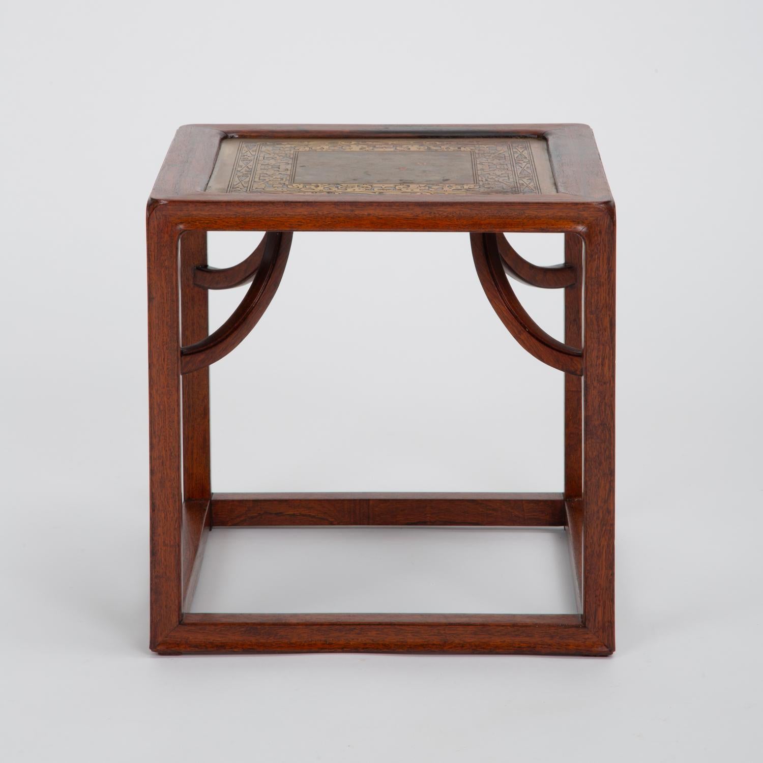 A cubic side table in rosewood and etched brass with subtle decorative motifs. Straddling modern and Arts & Crafts traditions, this square table has rounded edges and a layered construction with notched corners rounded edges. The frame is solid