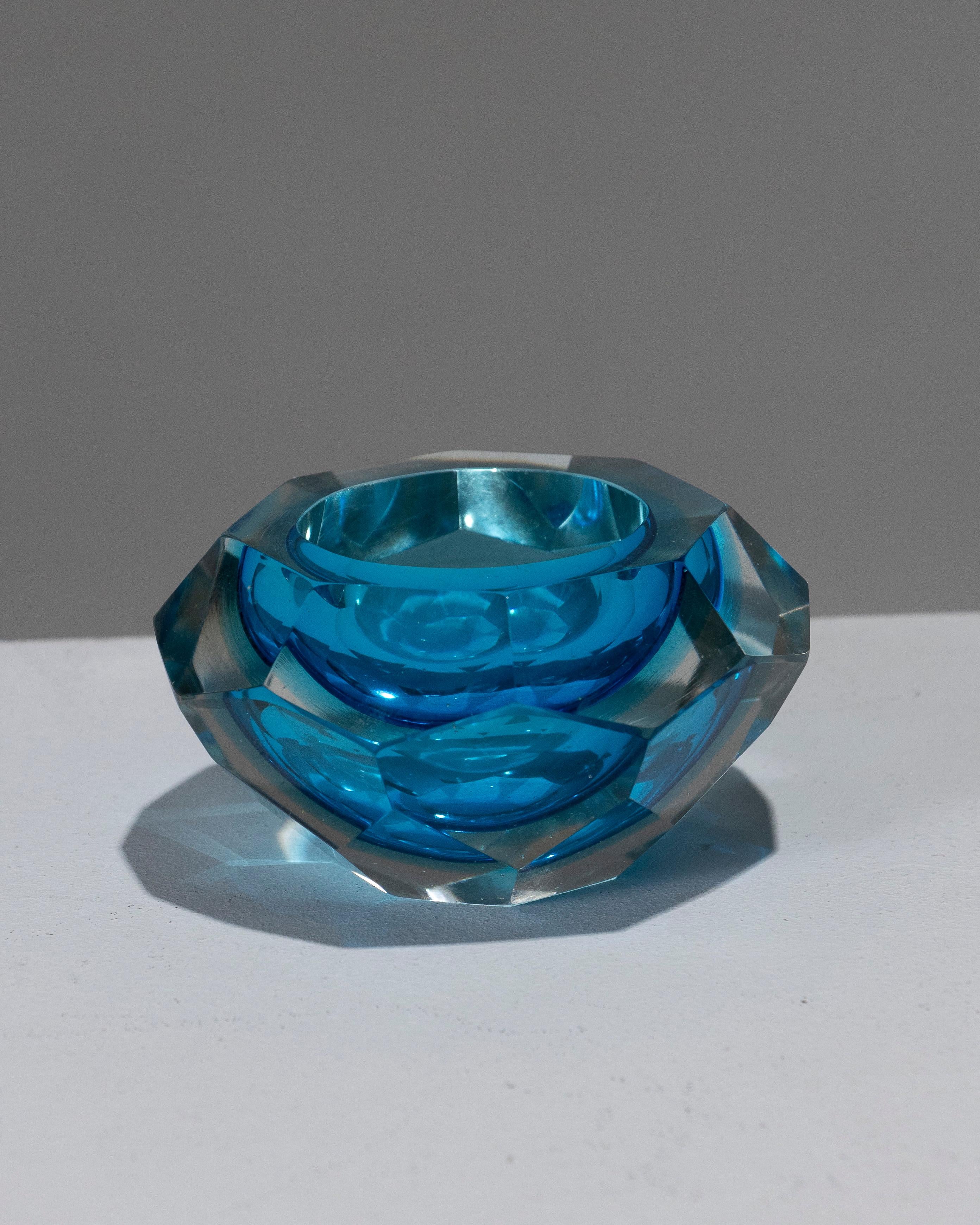 Small Cut Murano Glass Ashtray, crafted in Italy in the 1950s. Featuring multiple cut facets and a circular rim, in turquoise and transparent white. Very good condition.
DV1914
