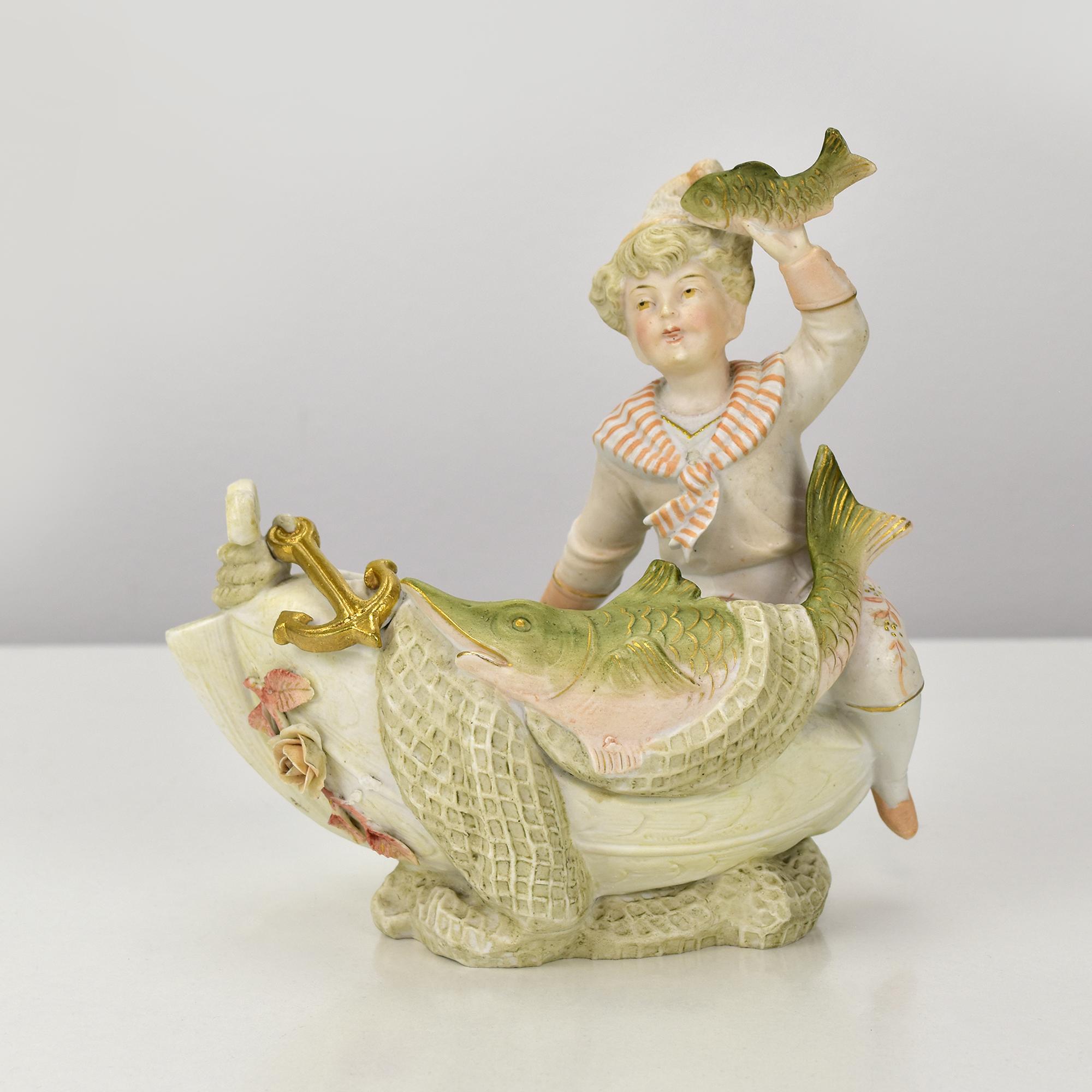 Petite jardinière en porcelaine en forme de bateau, représentant un petit garçon dans le rôle du capitaine qui brandit un poisson pêché. Les côtés sont décorés de filets de pêche et d'un grand esturgeon capturé.