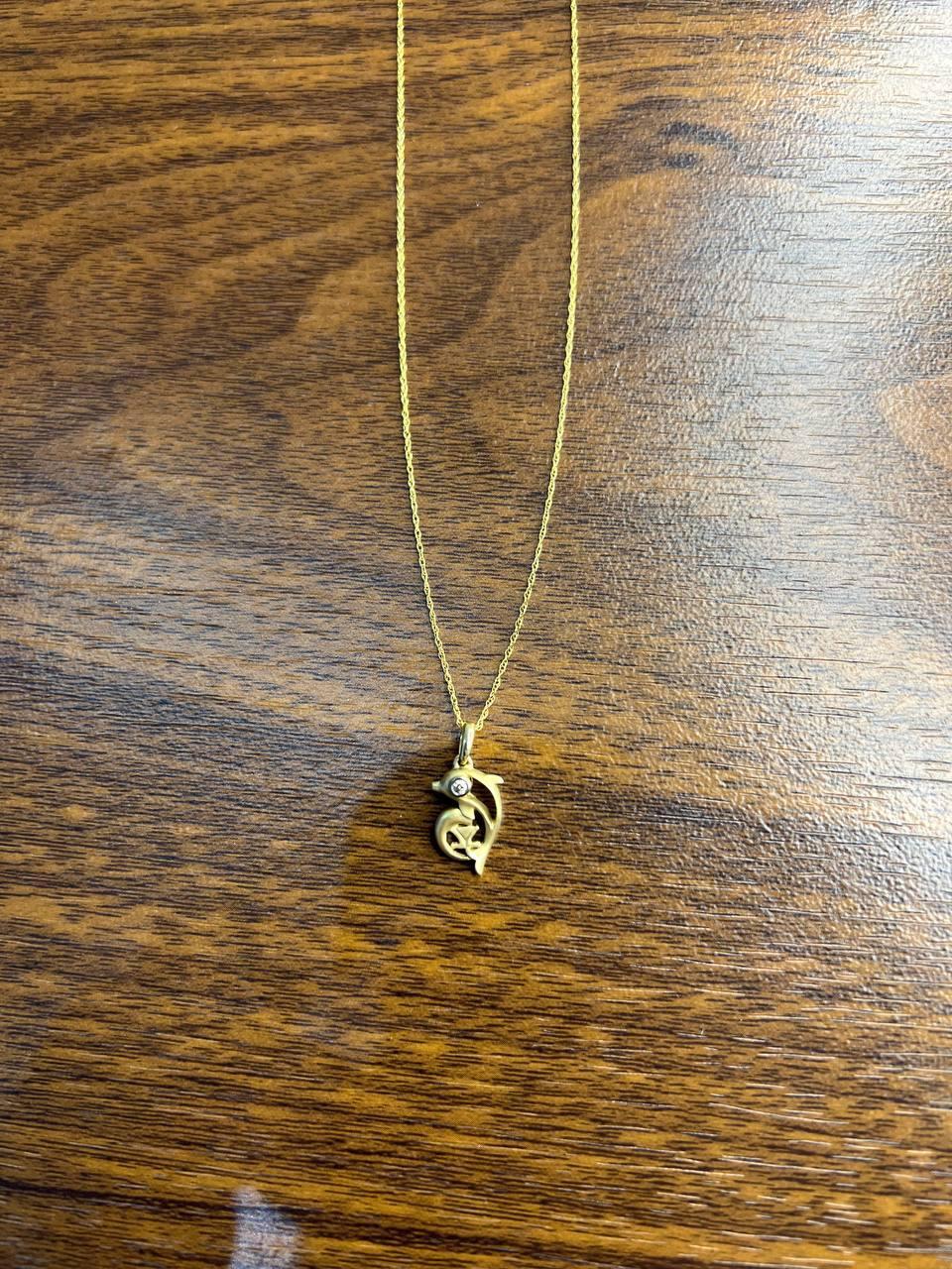 Un charmant pendentif en forme de dauphin.

Le pendentif présente un design de dauphin aux lignes épurées, s'enroulant élégamment autour d'un petit diamant étincelant. La forme du dauphin est lisse et polie, avec un équilibre délicat de courbes et