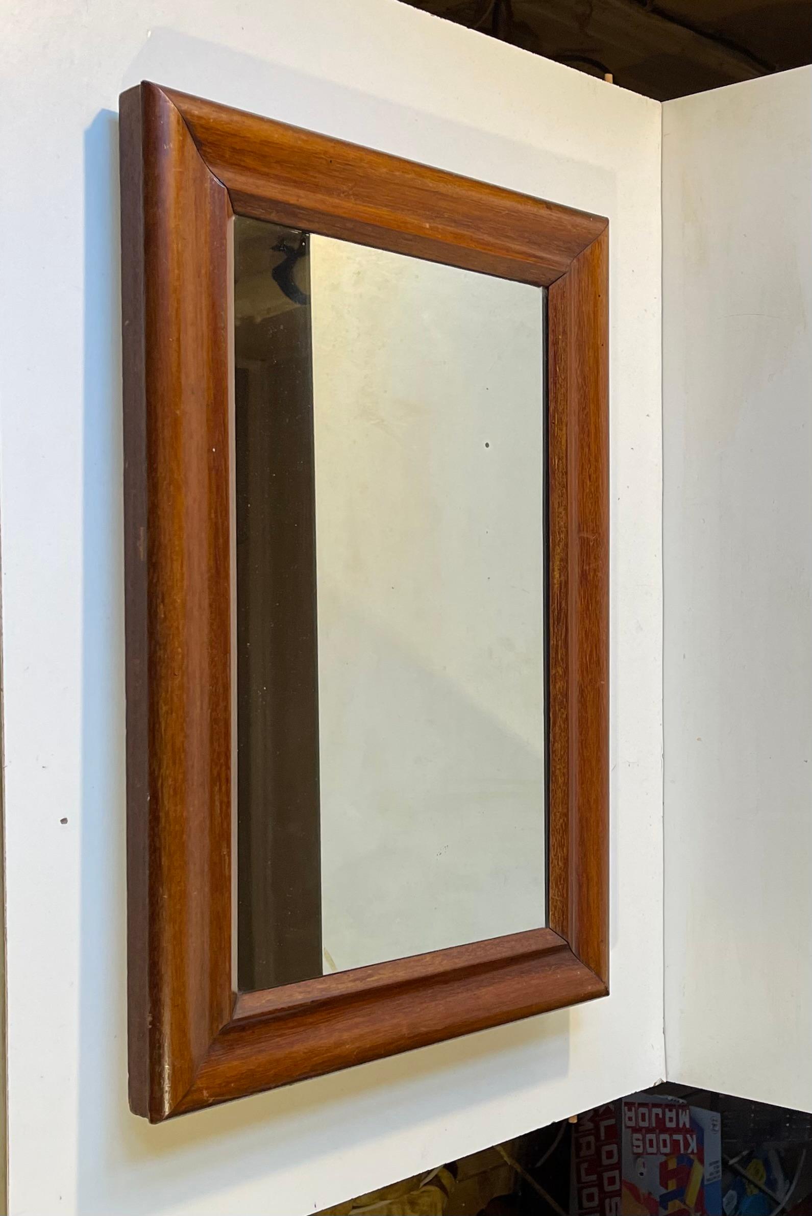 A small wall mirror in Mahogany veneer upon oak and pine. Clean curves and plain lines. Made by a Danish cabinetmaker during the early 1900s. Measurements: 52x36x4 cm in frame. The mahogany veneer used in this mirror frame can be exported freely