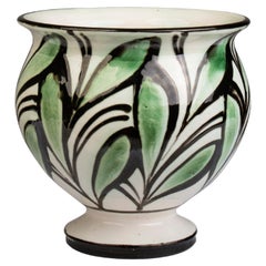 Pequeño jarrón danés de barro decorado con cuerno y hojas verdes sobre una base blanca 