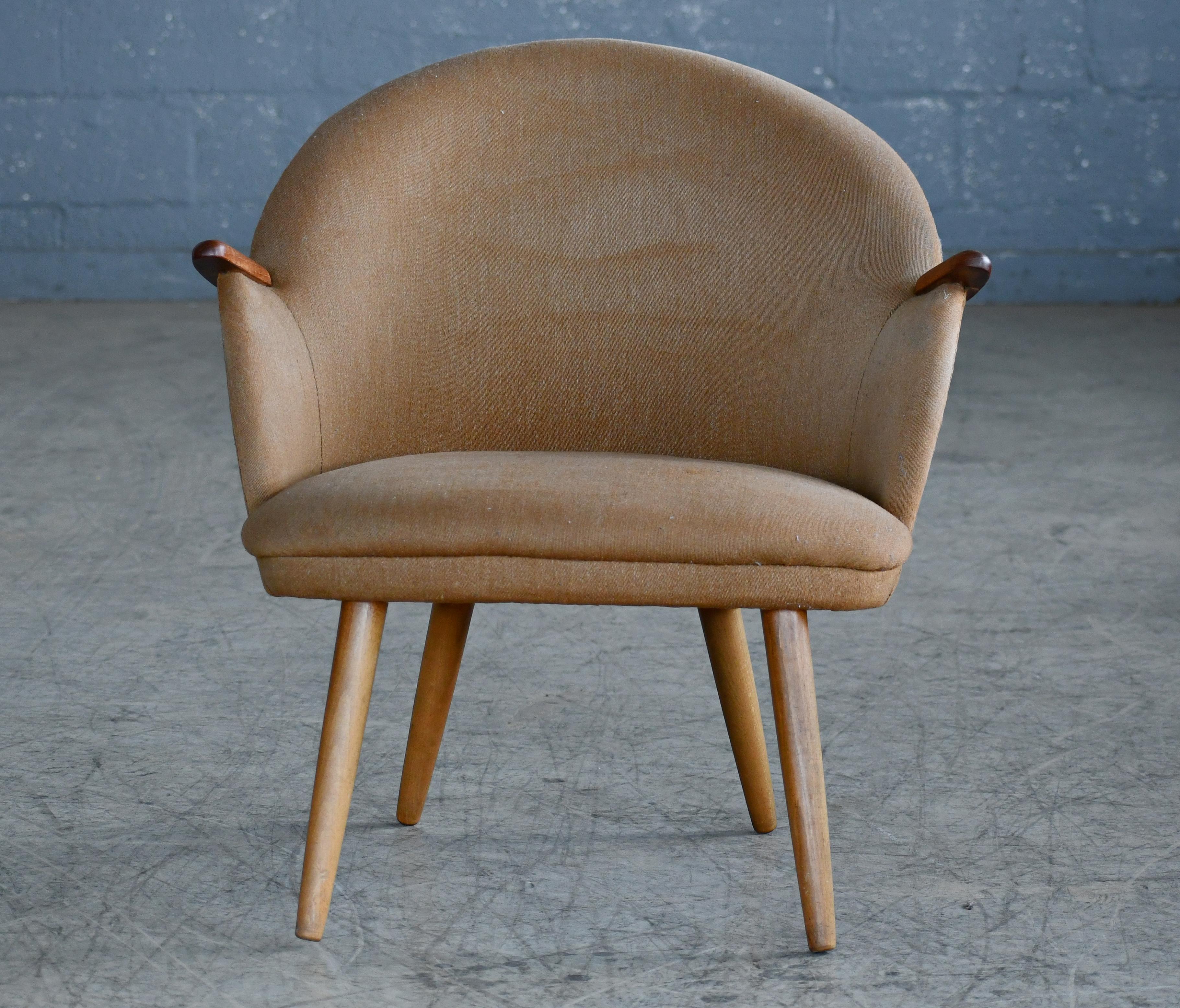 Great 1950s Danish lounge chair attributed to Kurt Olsen. The chair has some of the same of the same design lines as Hans Wegner's famous Mama Bear chair although a bit more compact. Solid teak armrests raised on legs of oak. Re-upholstered and
