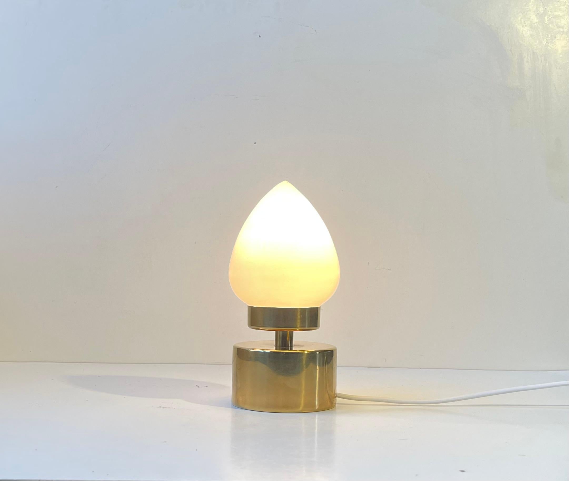 A small unusual table light fashioned from gold-chromed metal and featuring an egg shaped white opaline glass shade. It was made by Lyskær Belysning in Denmark during the 1980s. Suitable for cosy lighting or nautical/maritime settings.