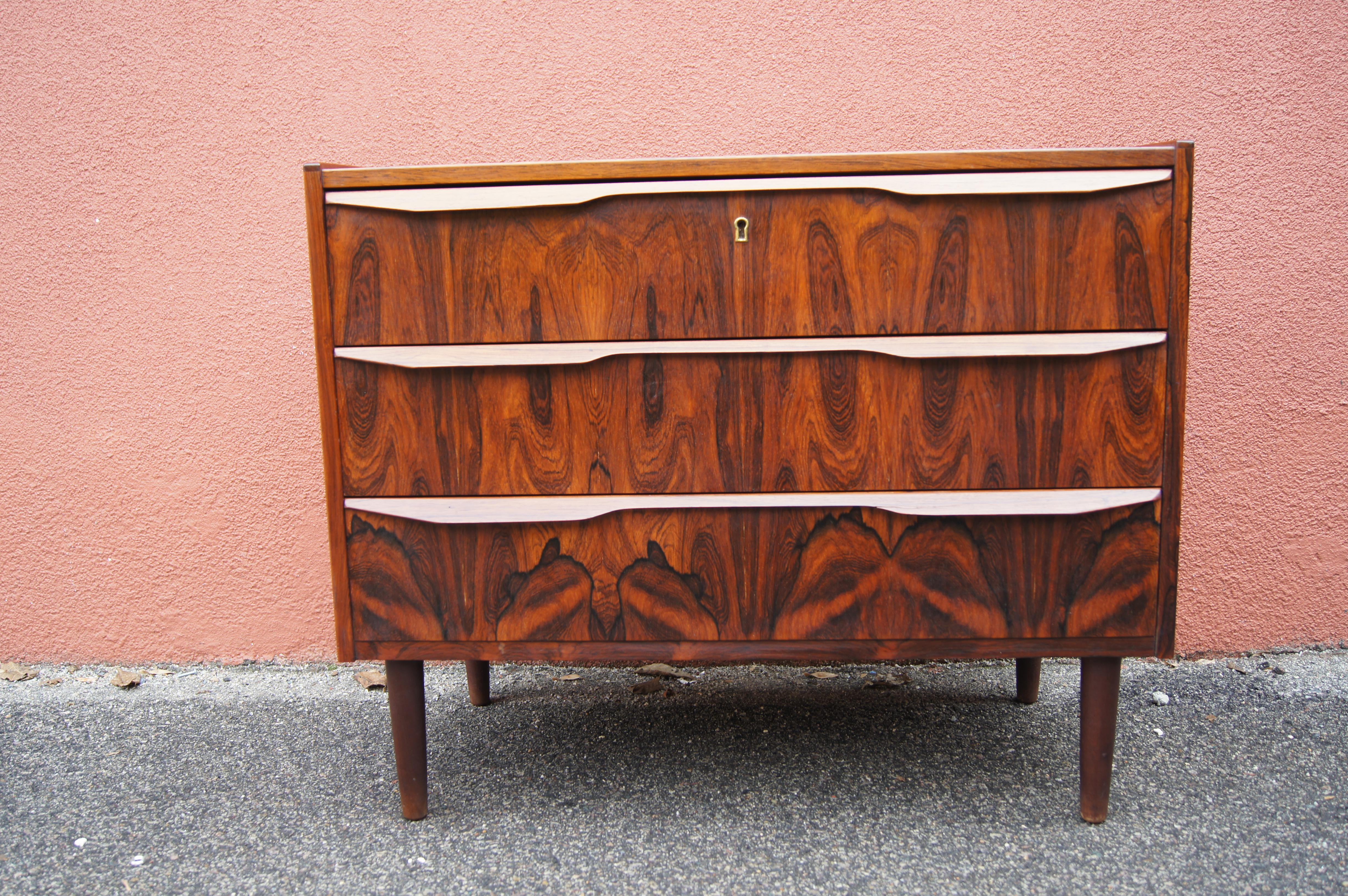 This handsome Danish modern chest features a vivid rosewood grain. Sculpted pulls extend across the width of its three drawers.

Comes with a working key.