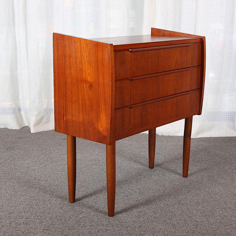 A smaller Danish teak three drawer mid century chest, the three drawers with elegant shaped top pulls, the whole raised on turned tapering legs.

 