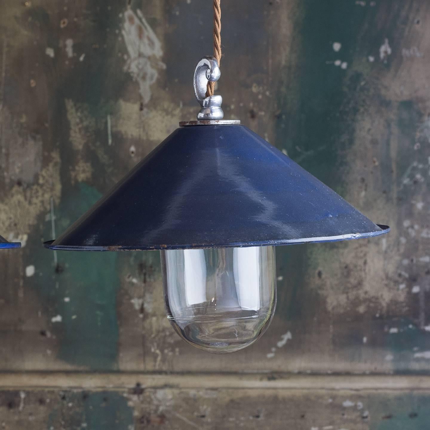 Small dark blue enamel pendant lights, with glass dome, re-wired and PAT tested with gold flex. Size of glass dome may vary, enamel shades with chips and scuffs commensurate with age.
 