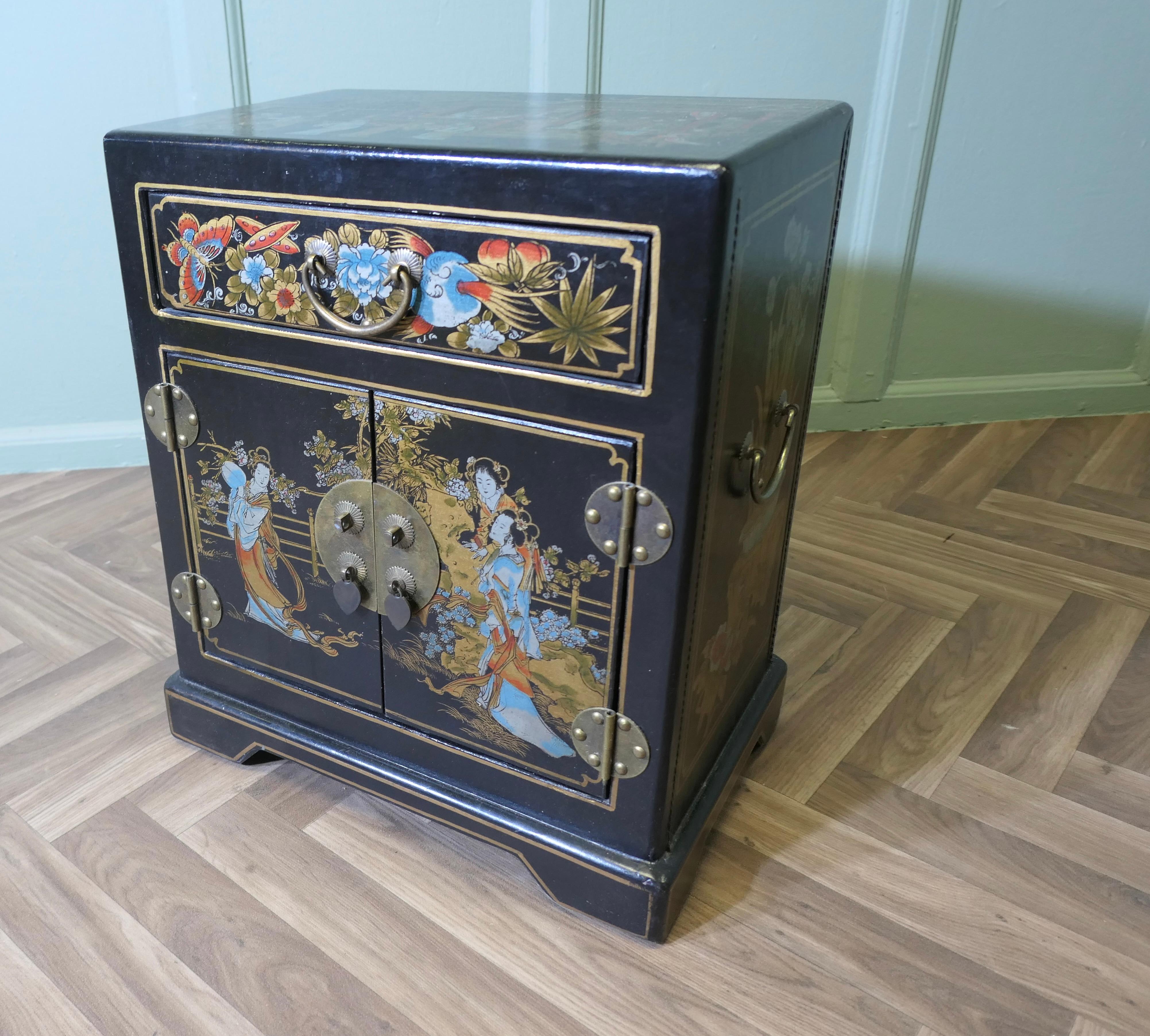 Piccola credenza decorata a cineserie

La credenza è in lacca nera e dipinta a colori con personaggi e fiori, ha un piccolo armadietto a due ante e un cassetto. 
Il mobile è molto bello e in buone condizioni d'uso. È alto 21