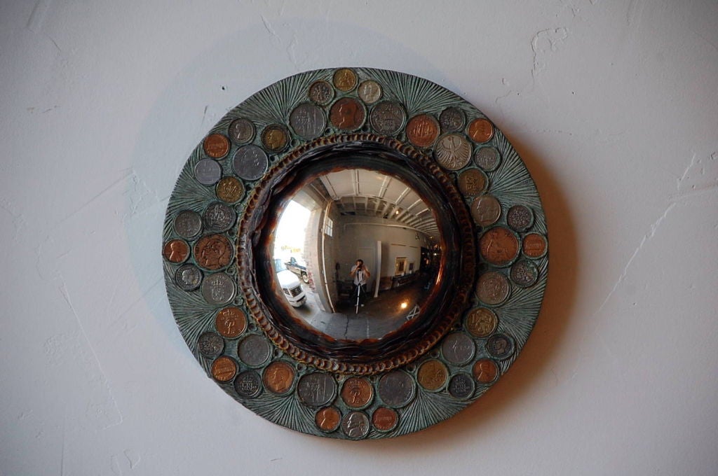 Small resin convex mirror with coin inclusions.