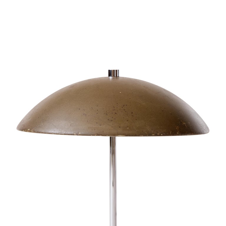 A small dome shaded desk lamp with a weighted base in a natural patina connected by a newly chromed stem.