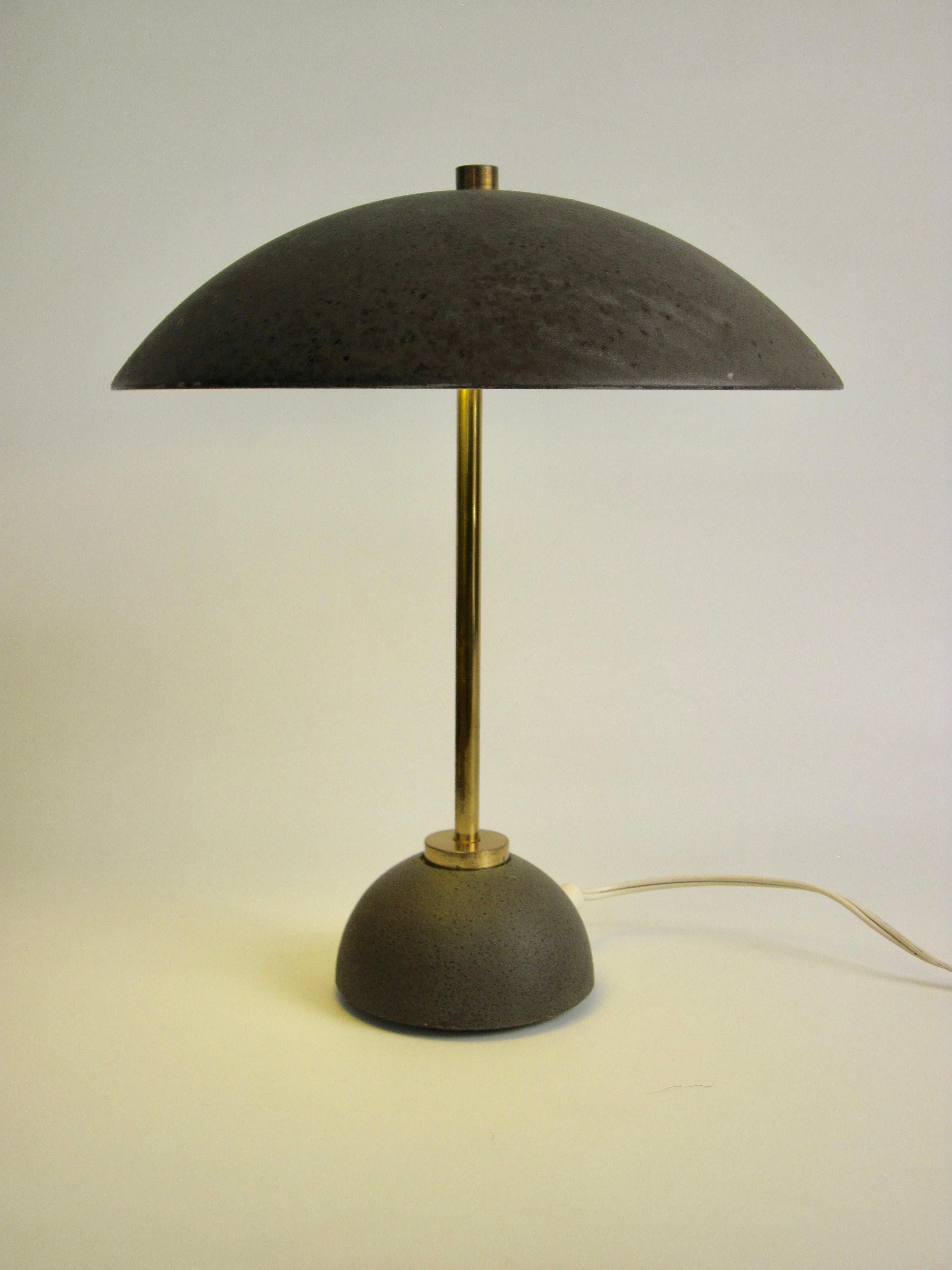 A small dome shaded desk lamp with a weighted base in army green with brass hardware.