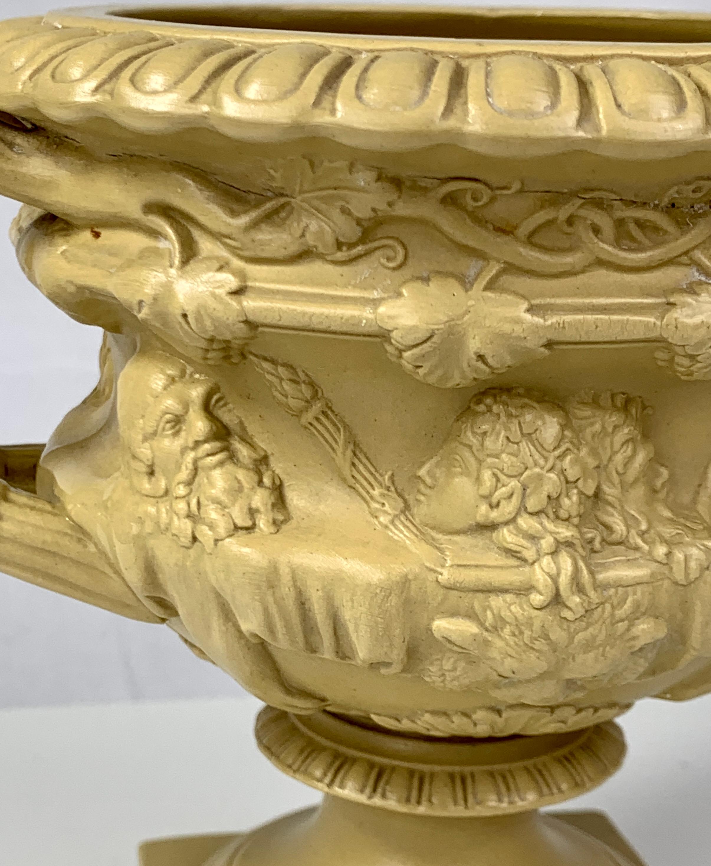 Ridgway made this drabware vase in England circa 1830. 
Pressed out in a mold, this eye-catching vase has high-relief neoclassical decoration consisting of Roman-style portraits under a band of grape leaves on the vine. 
The handles are in the form