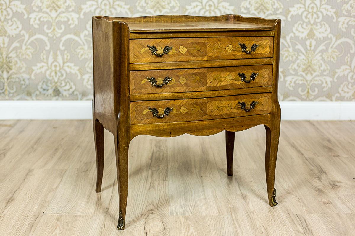 We present you this small dresser with a corpus with three drawers, which is supported on high, bentwood legs.
There is a small gallery on the top. Moreover, the top is ornamented with intarsia, similarly to the fronts of the drawers.
What adds
