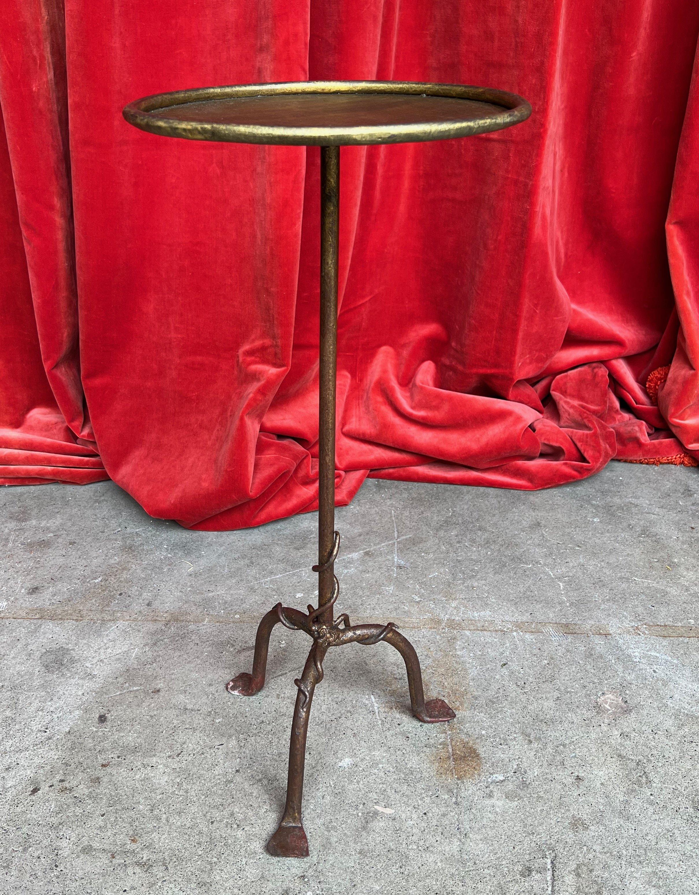 A charming Spanish small-scale iron and metal drinks table from the 1950s, perfect for adding a touch of vintage glamour to your space. This delightful table features an intriguing decorative detail on its tripod base, with a twisted and swirling