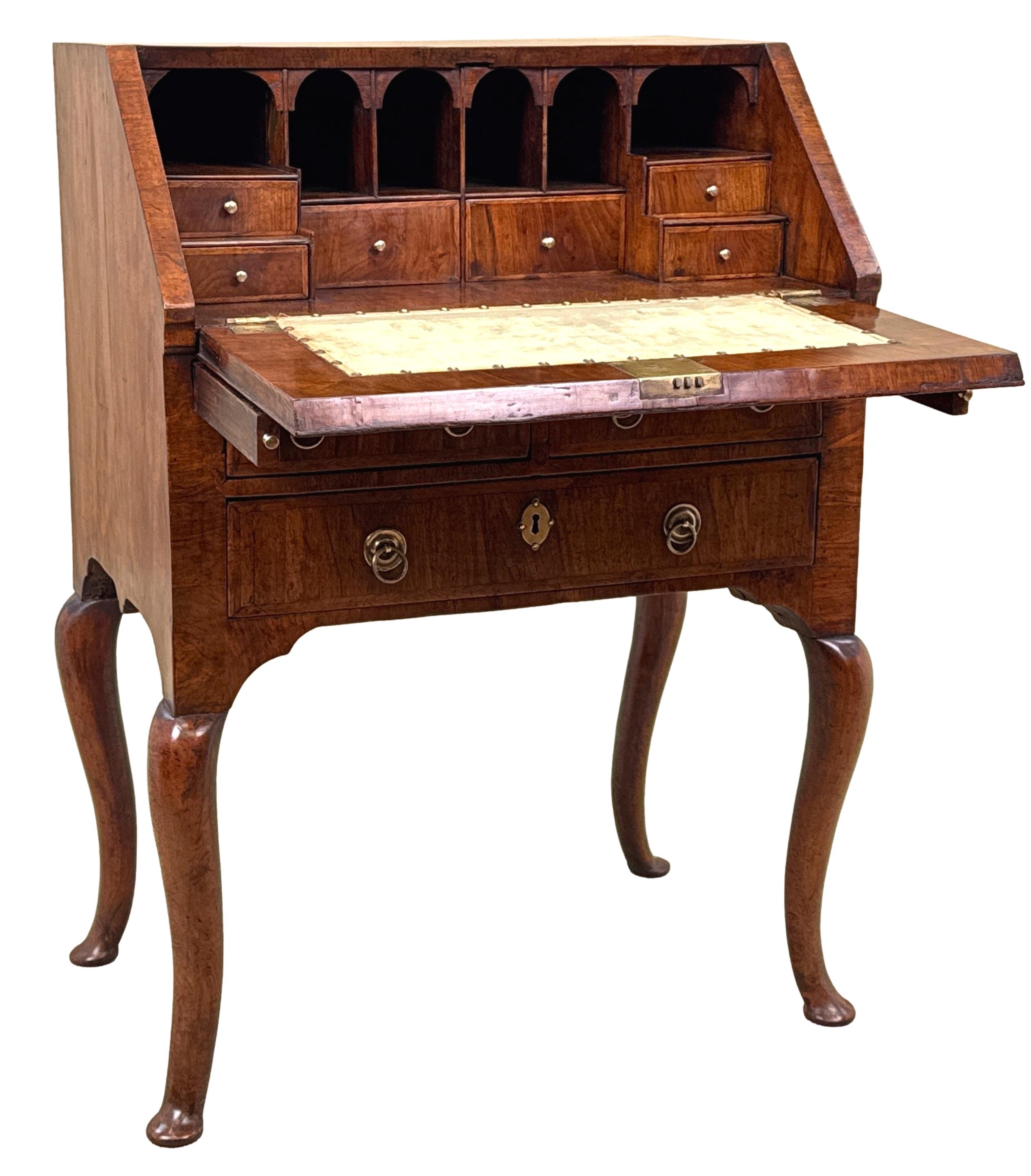 Un piccolo scrittoio in legno di noce, eccezionalmente raro, risalente all'inizio del XVIII secolo, periodo George I, con un piano superbamente modellato e un fronte inclinato, che racchiude un interno arredato, con decorazioni a fasce di piume in