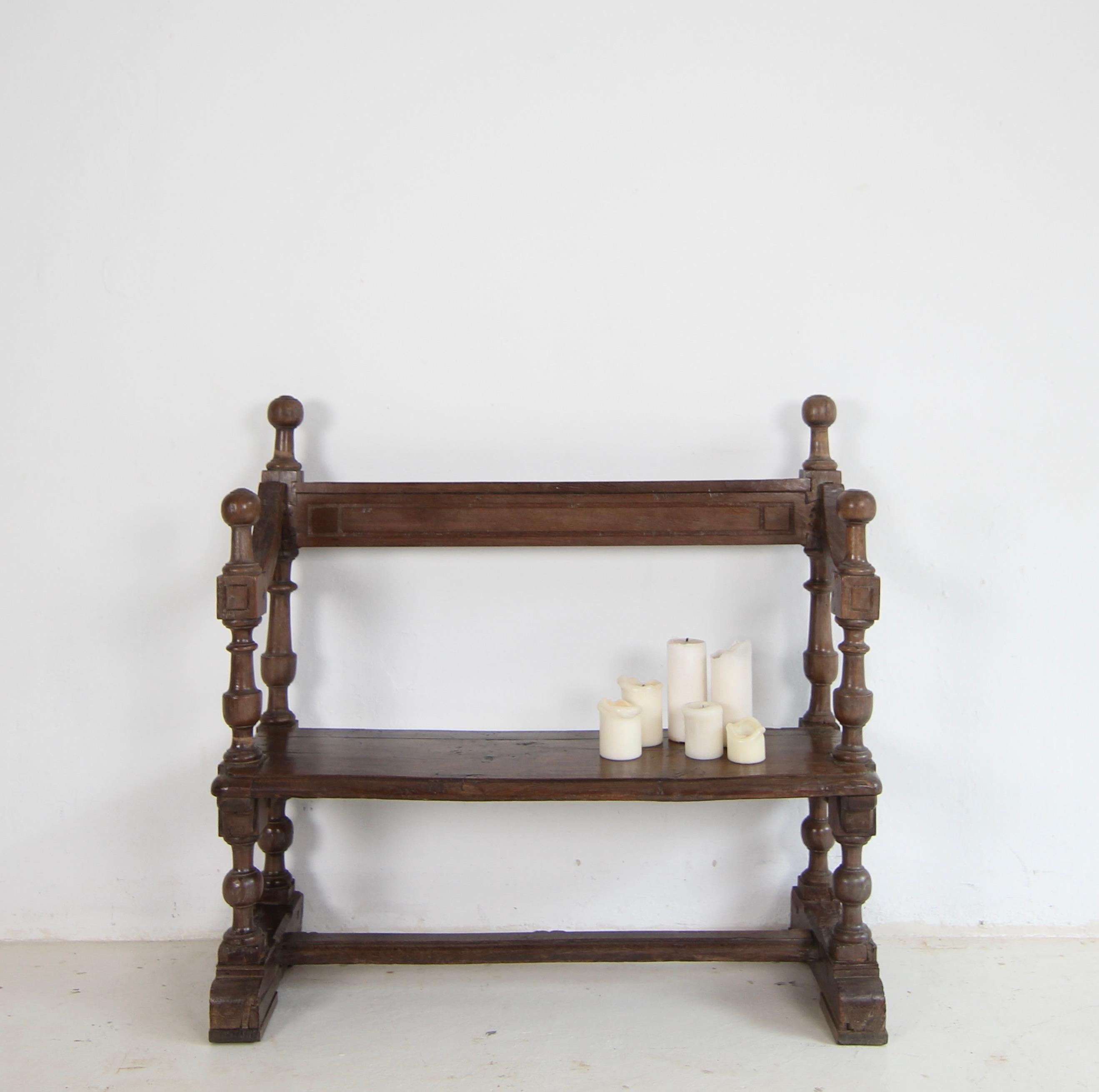 A rustic small church pew from the early 19th century. Made of solid oak wood, in great original condition.

Oak frame standing on 2 skids with bar connection consisting of 4 turned columns, solid moulded seat and narrow backrest with rear shelf for