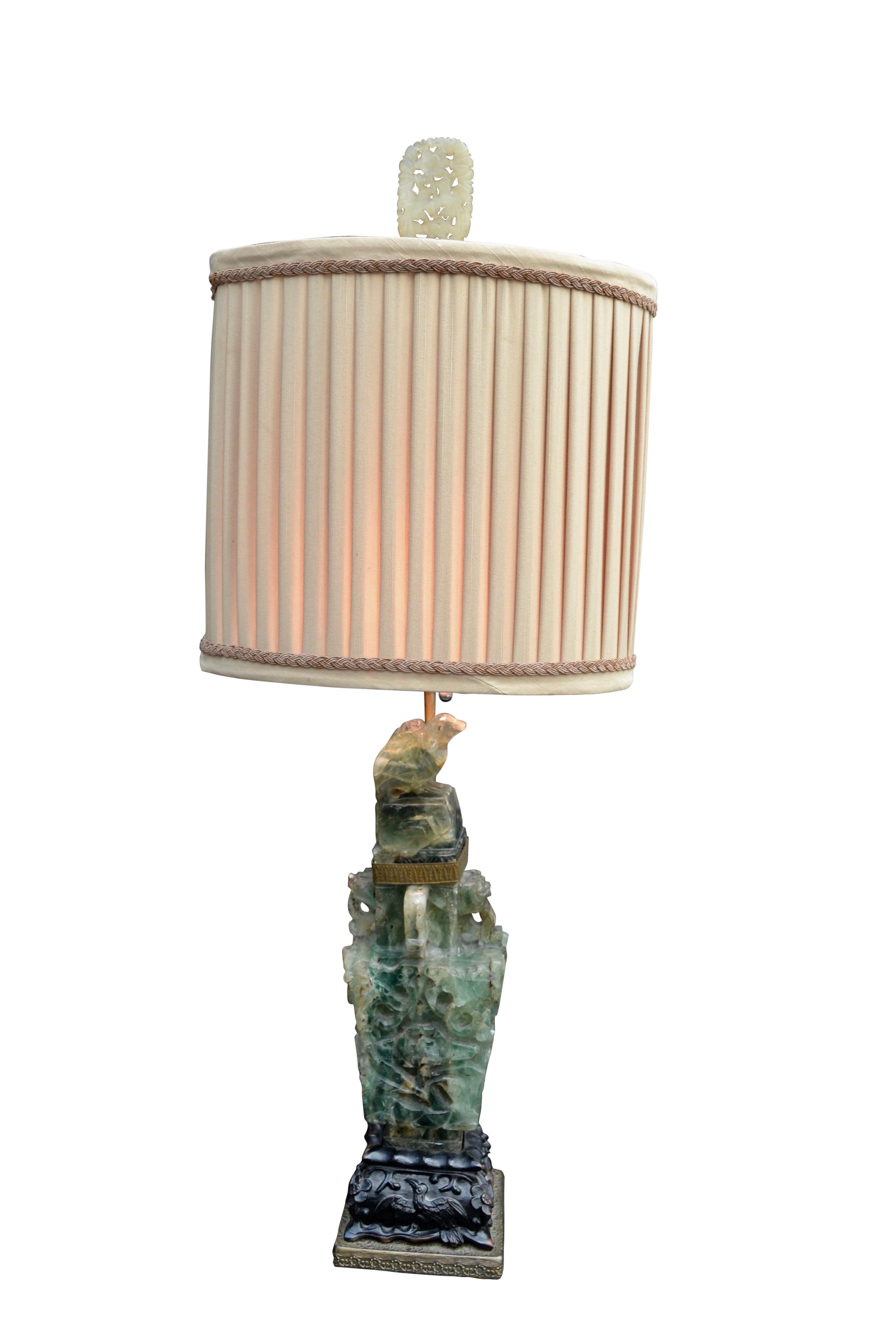 A relatively small but beautifully carved Chinese green quartz lamp with a removable carved bird top, set on a craved wood base. The lamp comes with a pleated silk shade and an original jade finial.