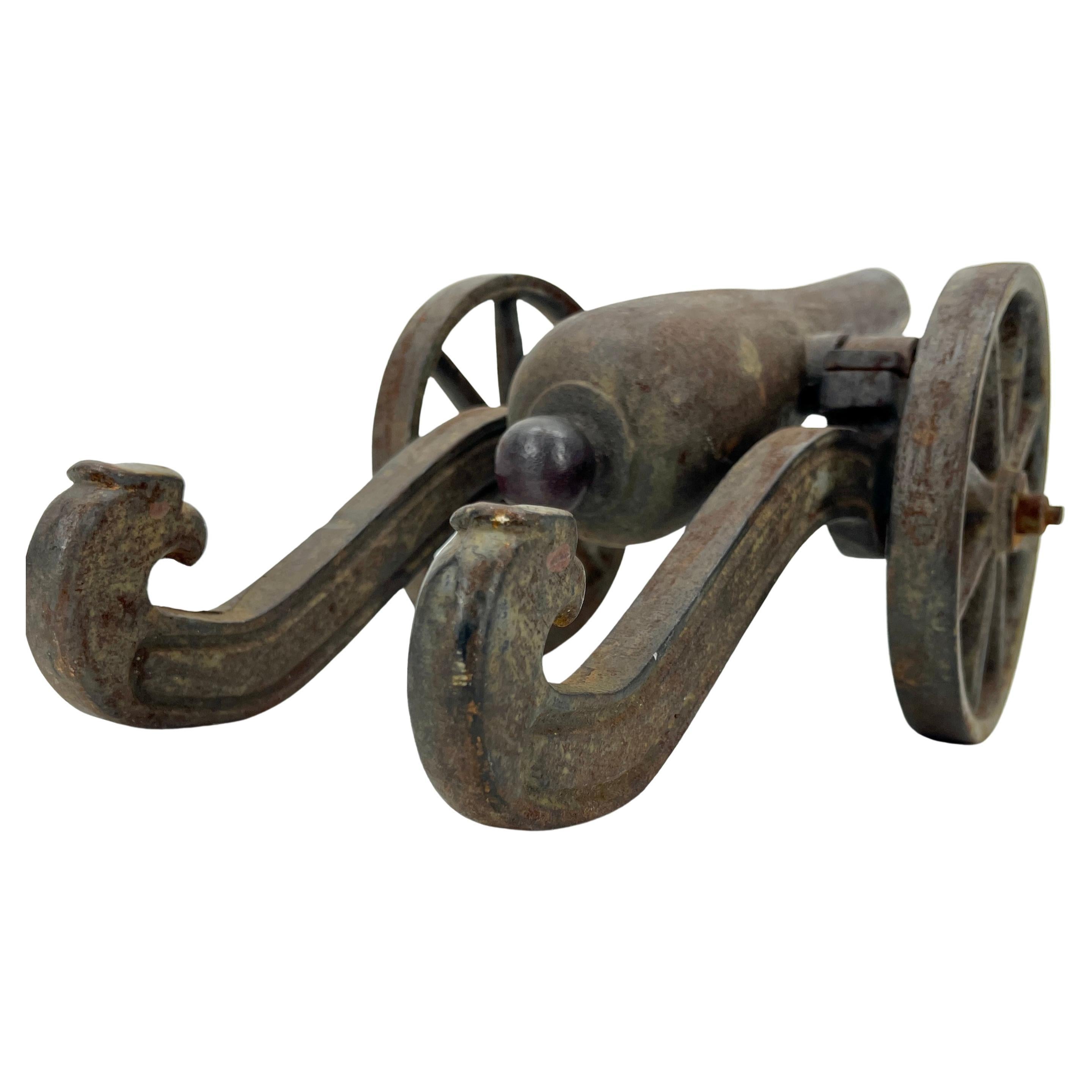 Canon miniature en fer de style civil américain sur roues avec décoration en forme de tête d'aigle.