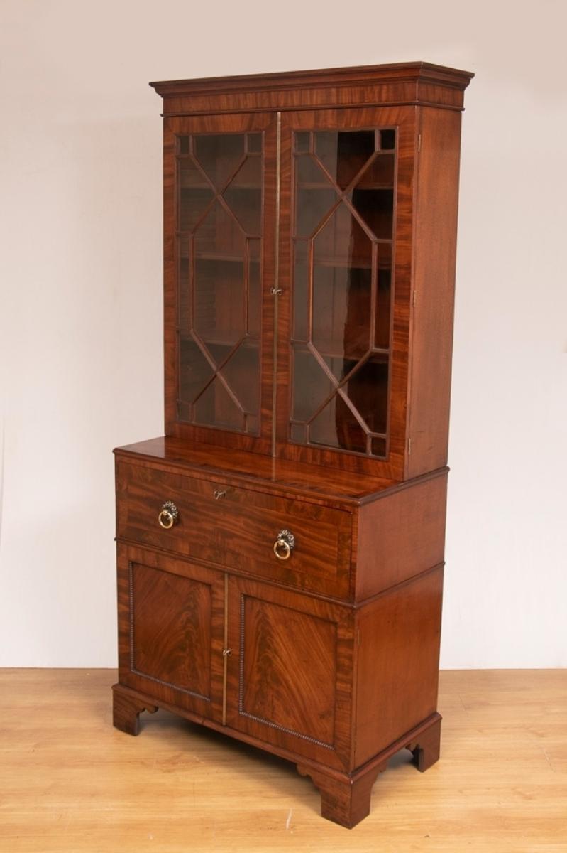 A small antique bookcase with a fold-out bureau made in mahogany with glazed doors.