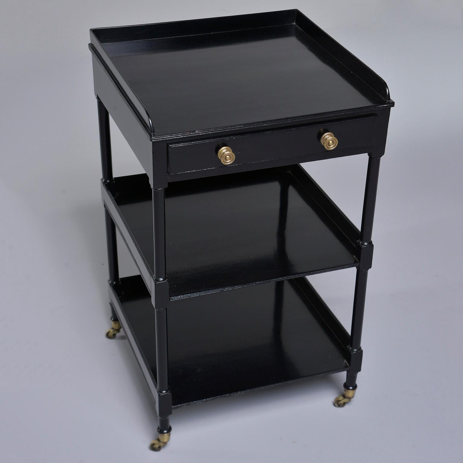 English mahogany three shelf étagère has a new ebonized finish, circa 1910. This piece features a single, functional drawer and original brass cup casters. Unknown maker.