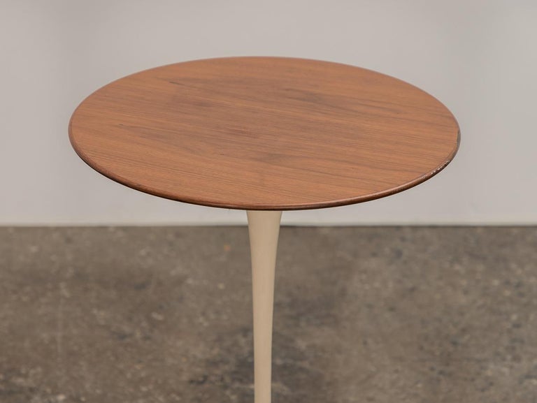 Early petite Tulip side table in walnut, designed by Eero Saarinen for Knoll. This is the smallest in the iconic Tulip Table Series. Polished walnut top has a wide, tapered edge which sits on the white curved base. A substantial weighted base