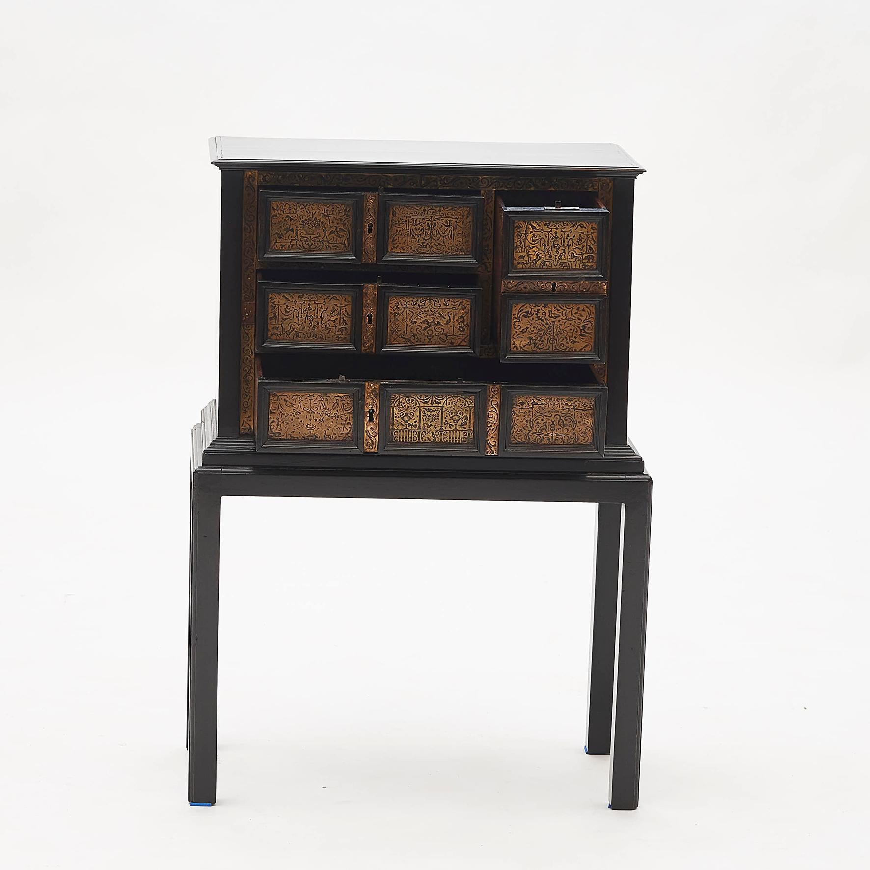 Small elegant baroque cabinet in ebonized wood. 4 drawers. Drawers and frame with ornamented brass engravings in the form of animals and people, Italy, circa 1700-1730. Later base.